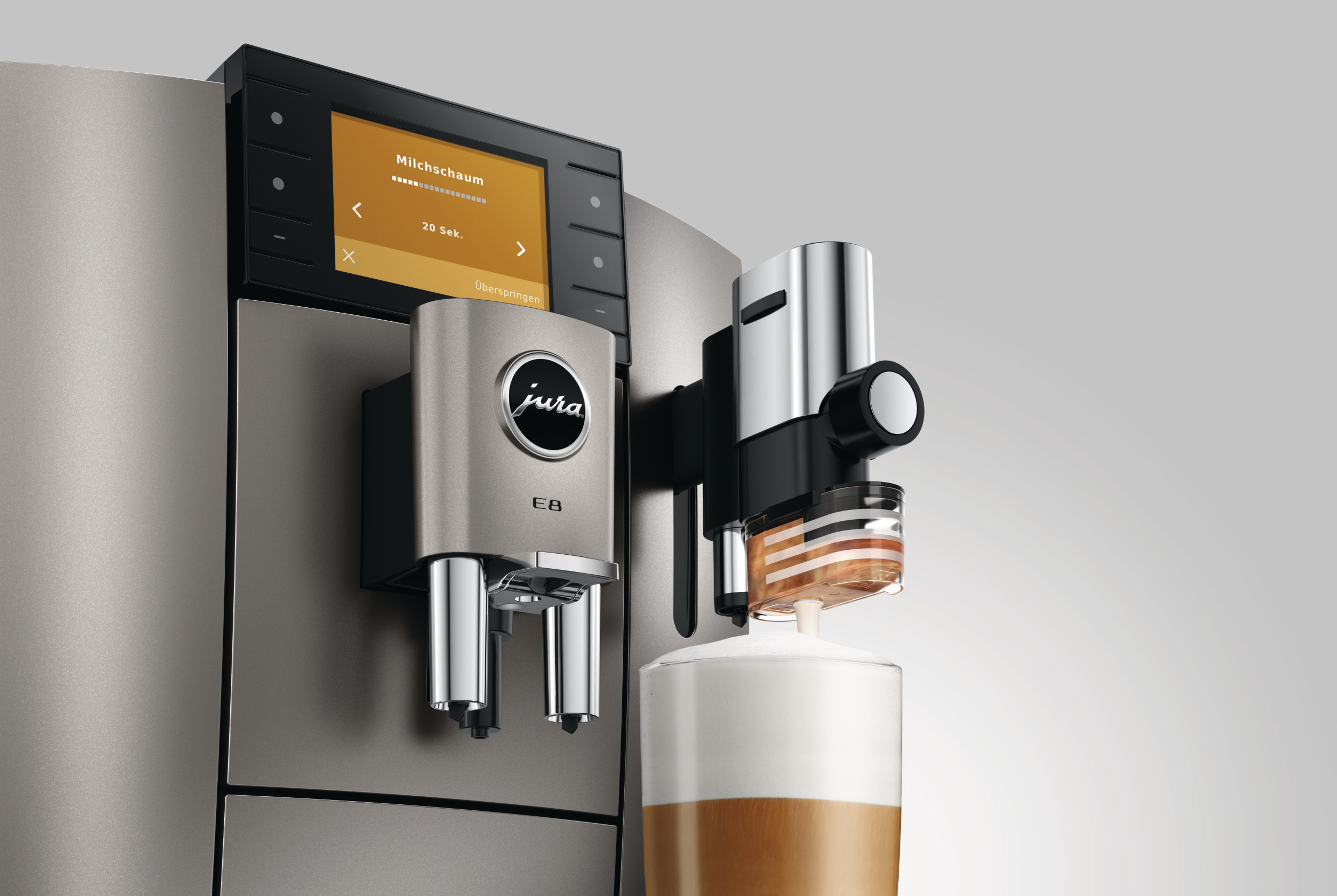 Eine Kaffeemaschine gibt Milchschaum in ein Glas aus. Die Maschine hat einen Bildschirm mit 'Milchschaum'.