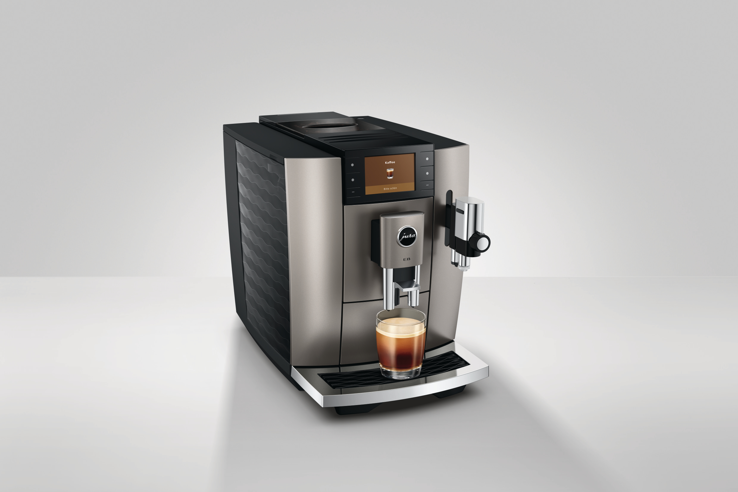 Eine Espressomaschine mit einer Tasse Kaffee. Sie hat ein silbernes und schwarzes Design mit einem Bildschirm und einem Markenlogo.
