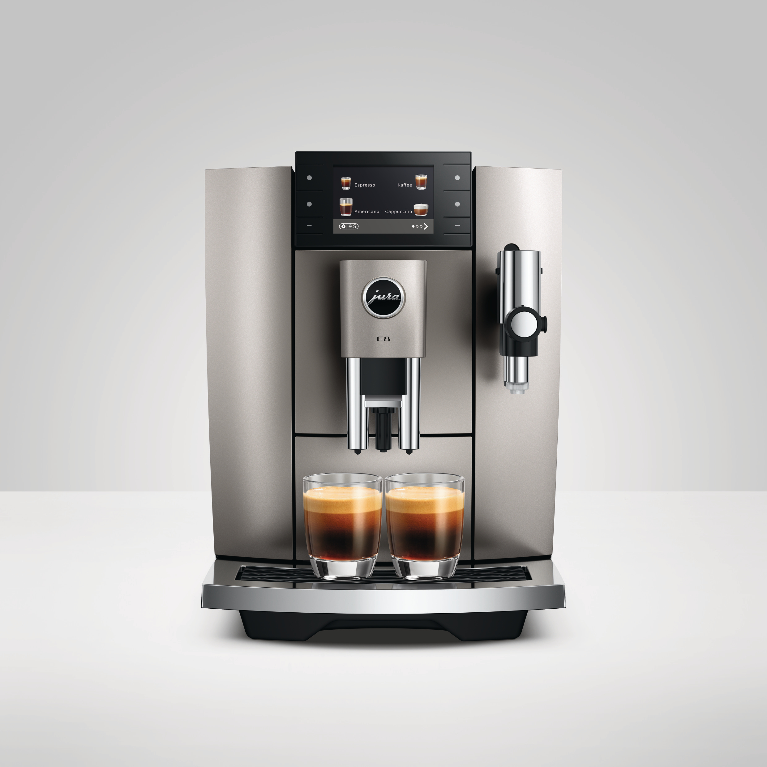 Eine silberne Jura E8 Kaffeemaschine, zwei Espressogläser mit Kaffee gefüllt und ein schwarzes Display.