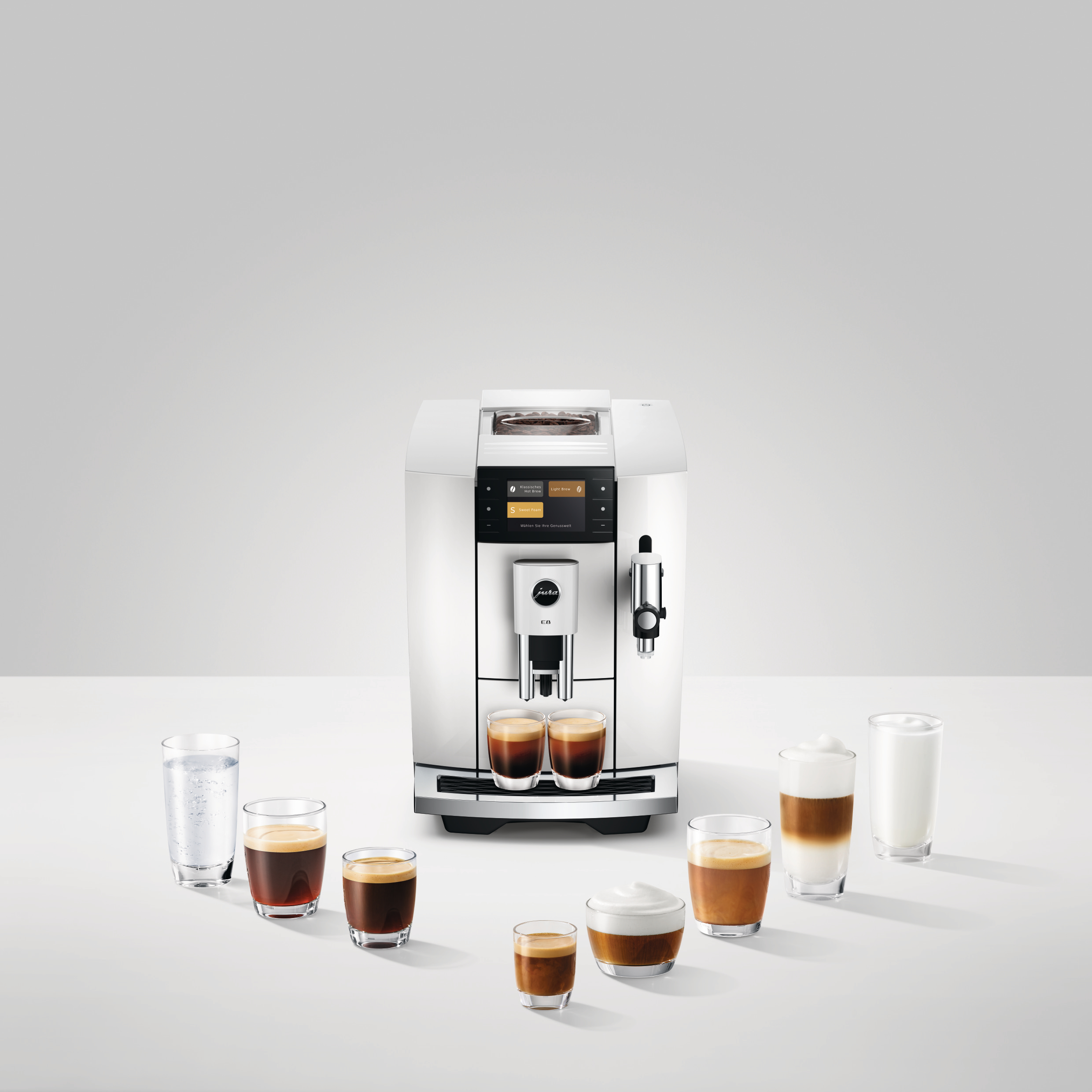 Weiße Kaffeemaschine mit Kaffeetassen. Espresso, Cappuccino, Latte und Wassergläser sind darum herum.