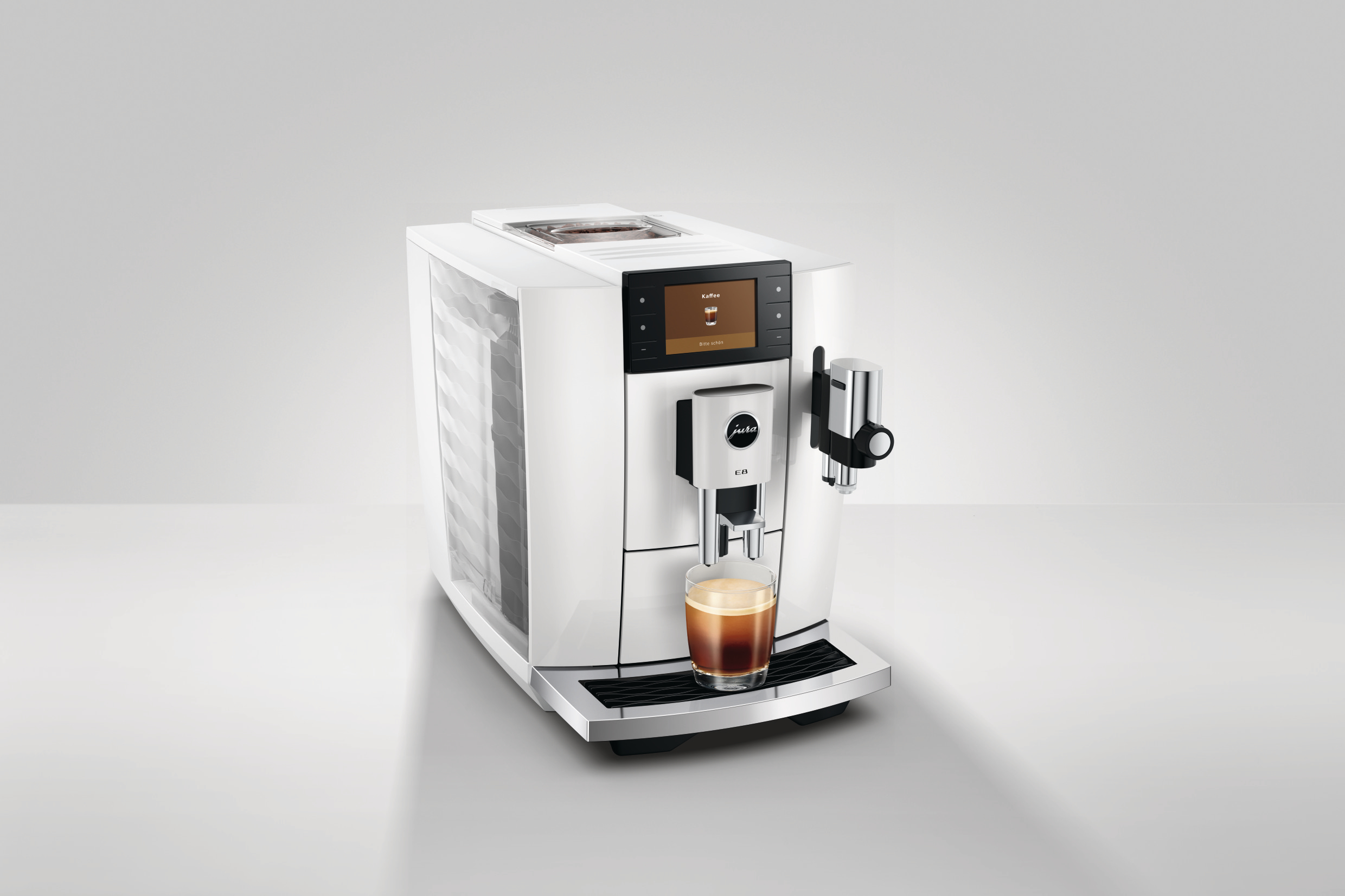 Eine weiße und silberne Jura E8 Kaffeemaschine. Unter dem Ausguss steht ein Glas Kaffee. Die Maschine hat einen Bildschirm.