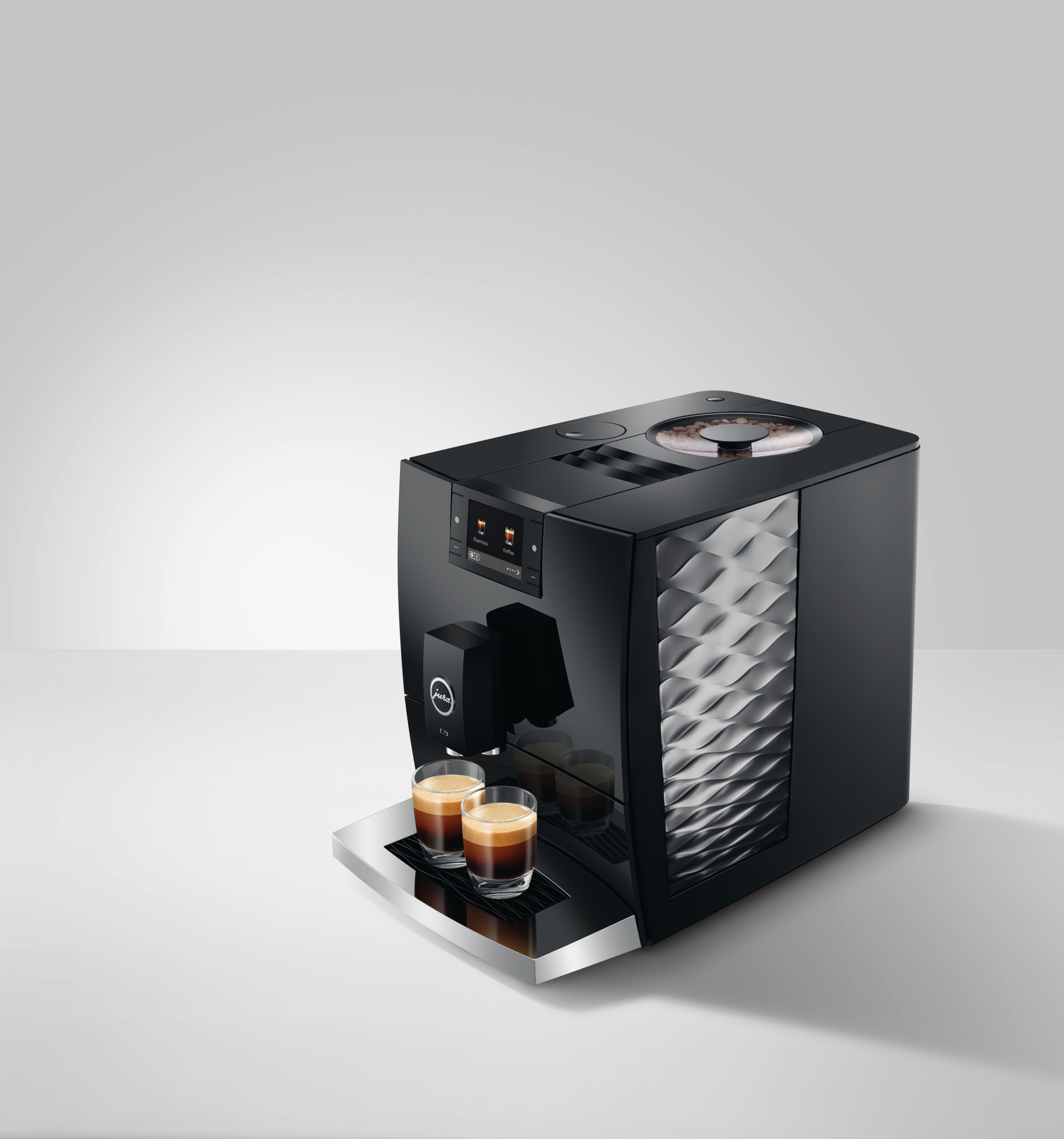 Eine schwarze Jura-Kaffeemaschine mit zwei Espresso-Shots in Gläsern. Die Maschine steht auf einer weißen Oberfläche.