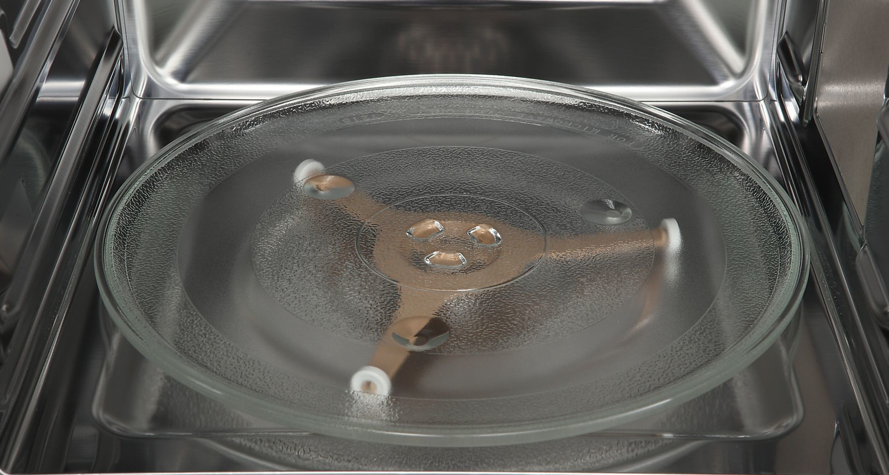 Wewnątrz kuchenki mikrofalowej szklany talerz spoczywa na mechanizmie obrotowym. Wnętrze jest ze stali nierdzewnej.