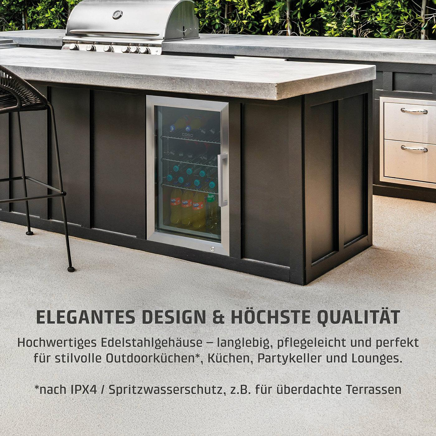 Outdoorküche mit Grill, Kühlschrank mit Getränken und Barhocker. Dunkle Schränke und Betonarbeitsplatte. Grüne Büsche im Hintergrund.