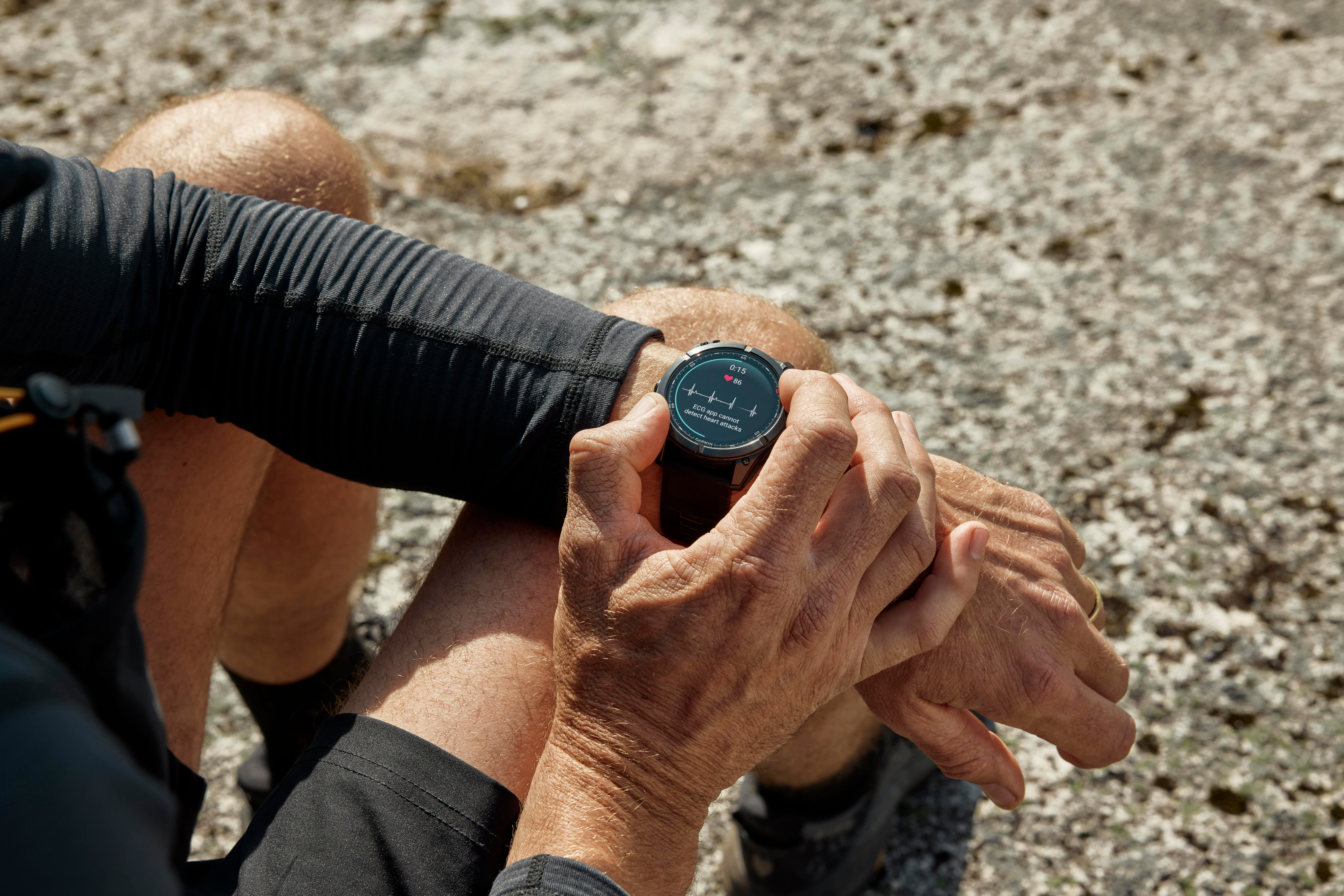 Eine Person, die eine Smartwatch trägt, überprüft ihre Herzfrequenz. Die Uhr zeigt Zeit und Herzfrequenzdaten. Der Hintergrund ist felsiges Gelände.