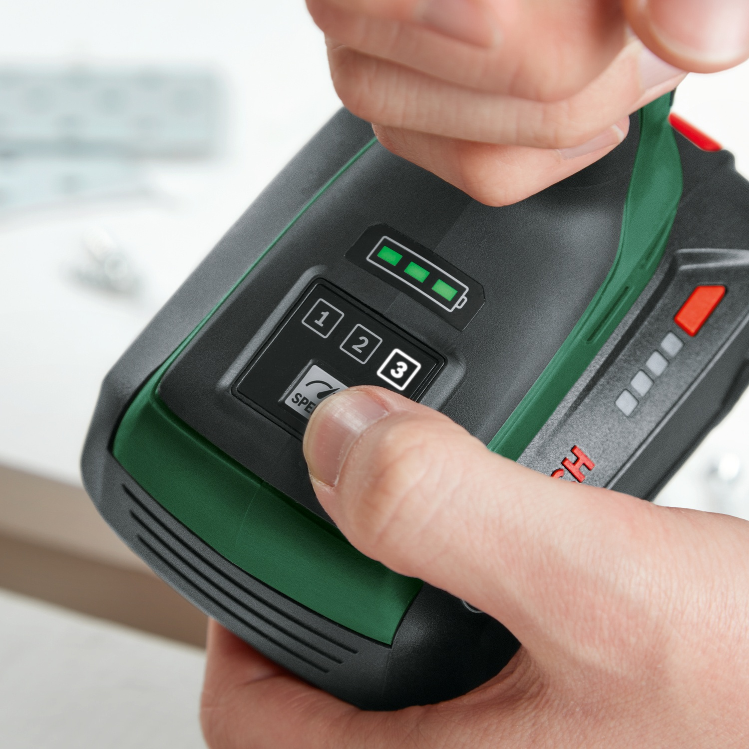 Una mano preme un pulsante su un utensile elettrico nero e verde. Lo strumento mostra la durata della batteria e le impostazioni di velocità. Il logo Bosch è visibile.