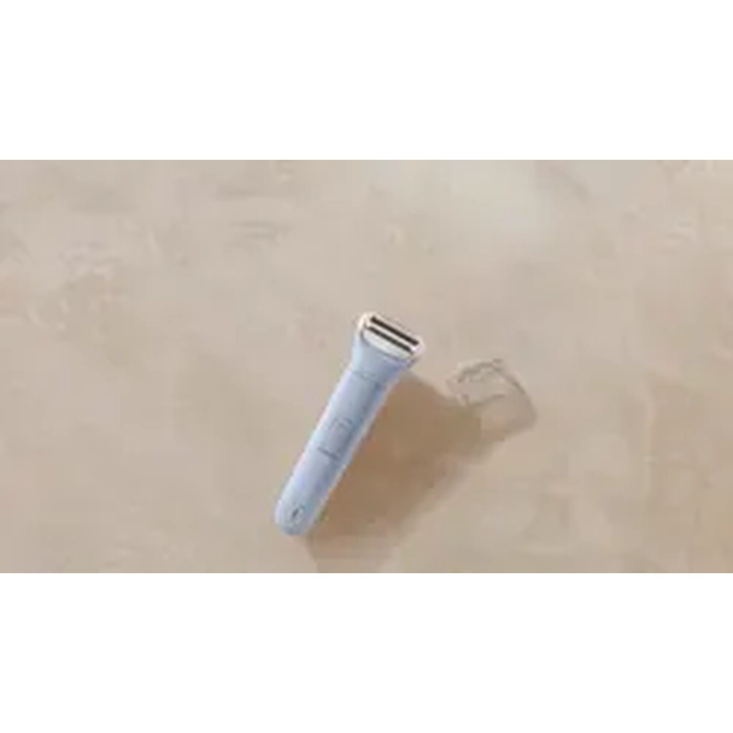 Un rasoio elettrico blu su una superficie beige. Il rasoio proietta un'ombra a destra.