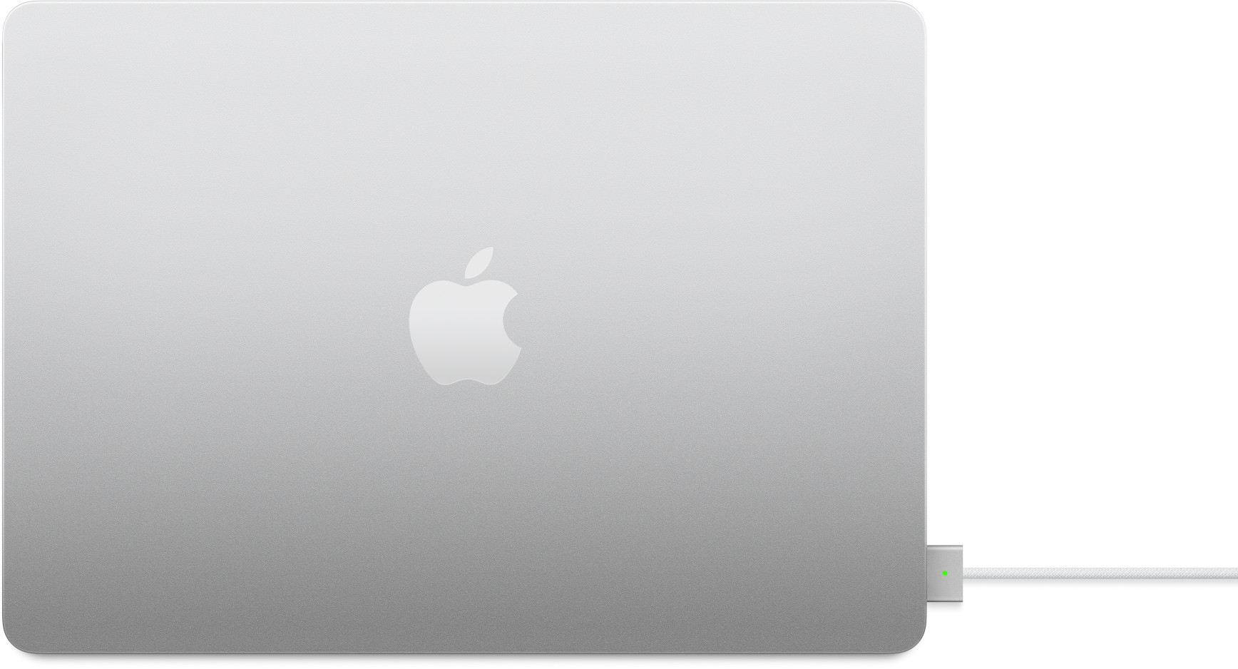 Ezüst MacBook Apple logóval. Töltő van csatlakoztatva. A háttér fehér.