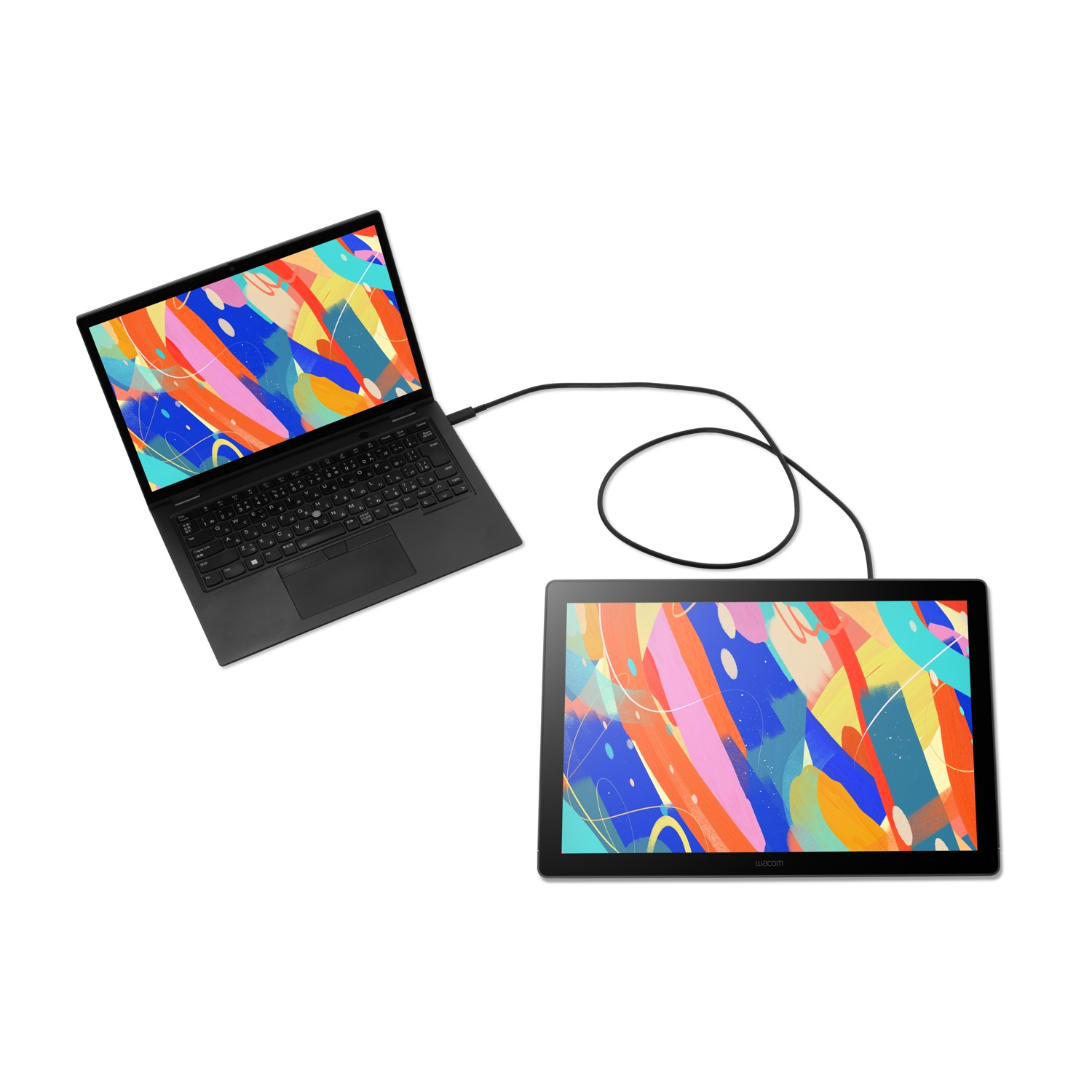 Laptop nero e tavoletta grafica collegati tramite cavo. Entrambi gli schermi mostrano arte astratta colorata su sfondo bianco.
