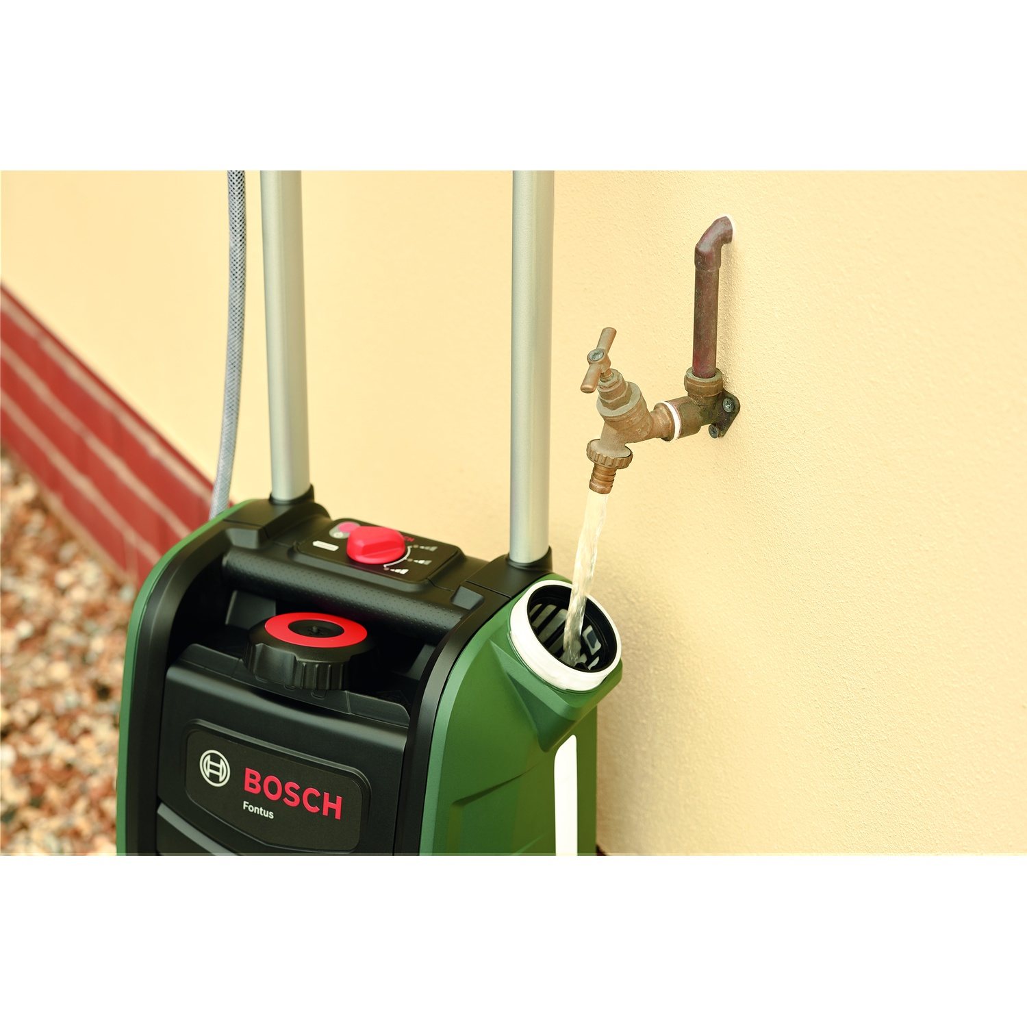 Un pulitore ad acqua Bosch Fontus verde e nero. L'acqua scorre da un rubinetto nel pulitore. Lo sfondo è un muro giallo chiaro.