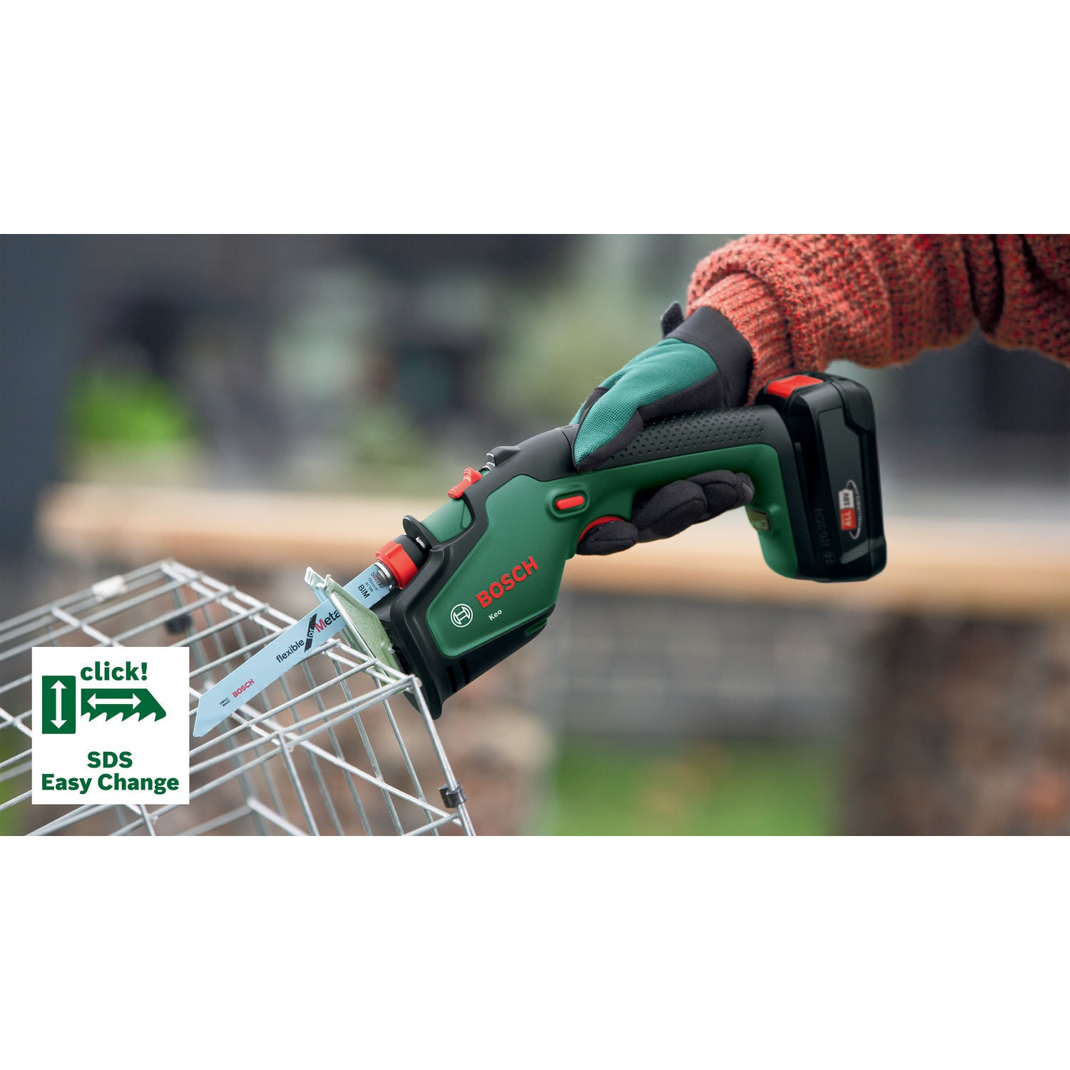 Una persona con guanti usa un seghetto Bosch verde e nero per tagliare una gabbia di metallo. Il seghetto ha una batteria e 'SDS Easy Change'.