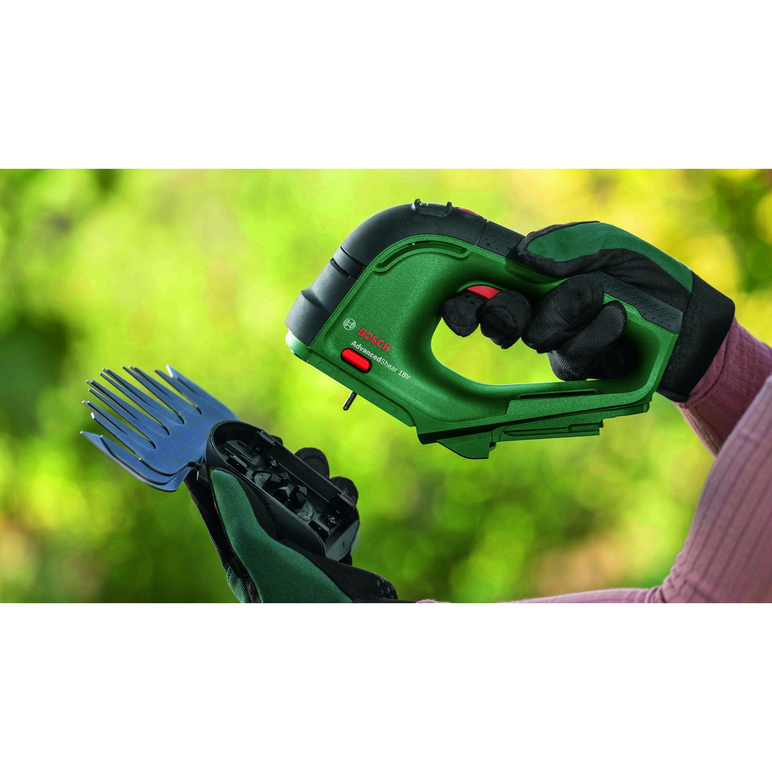 Una persona tiene in mano una cesoia elettrica Bosch verde. La cesoia è abbinata a un accessorio blu a forma di forchetta. La persona indossa guanti da giardinaggio.