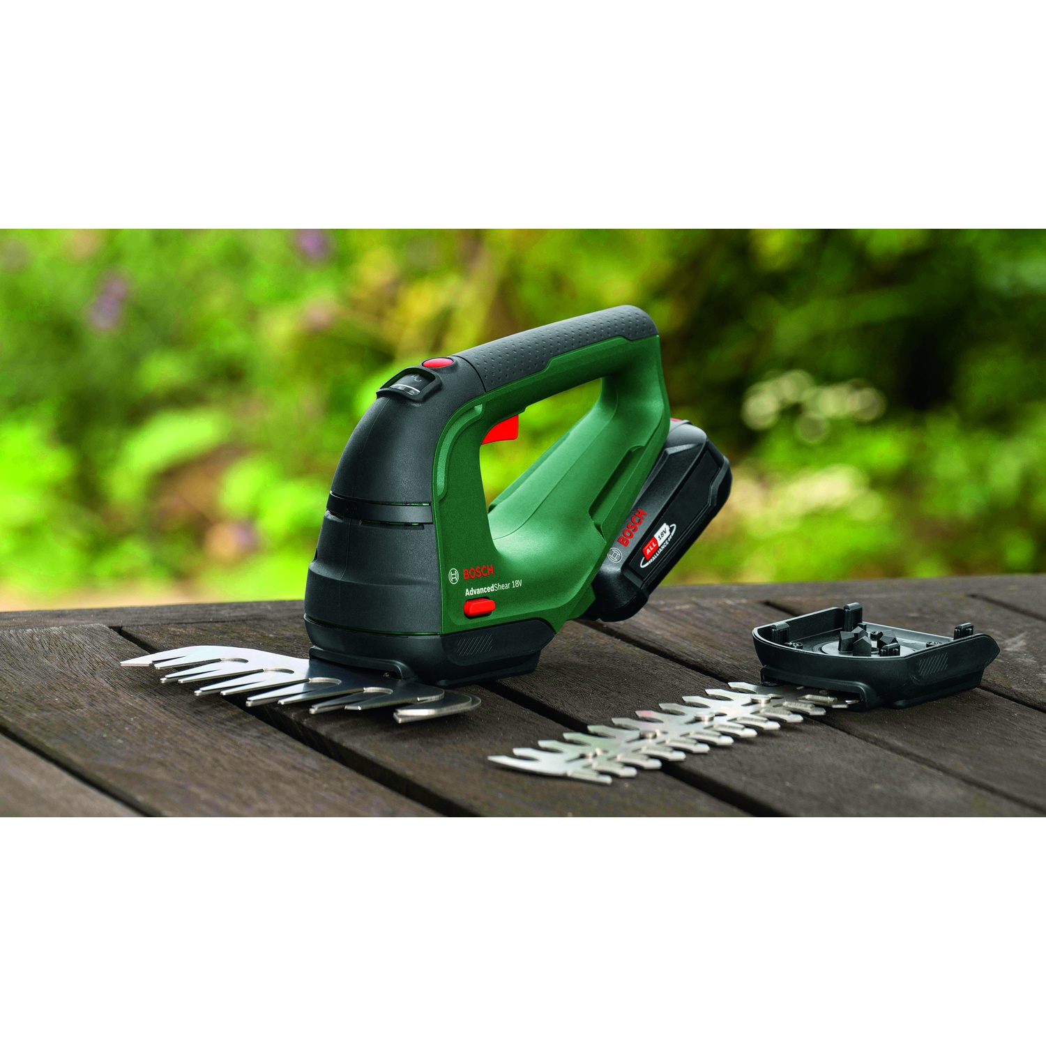 Un tagliasiepi Bosch AdvancedShear 18V verde e nero con lame, batteria e accessorio lama aggiuntivo su un tavolo di legno.