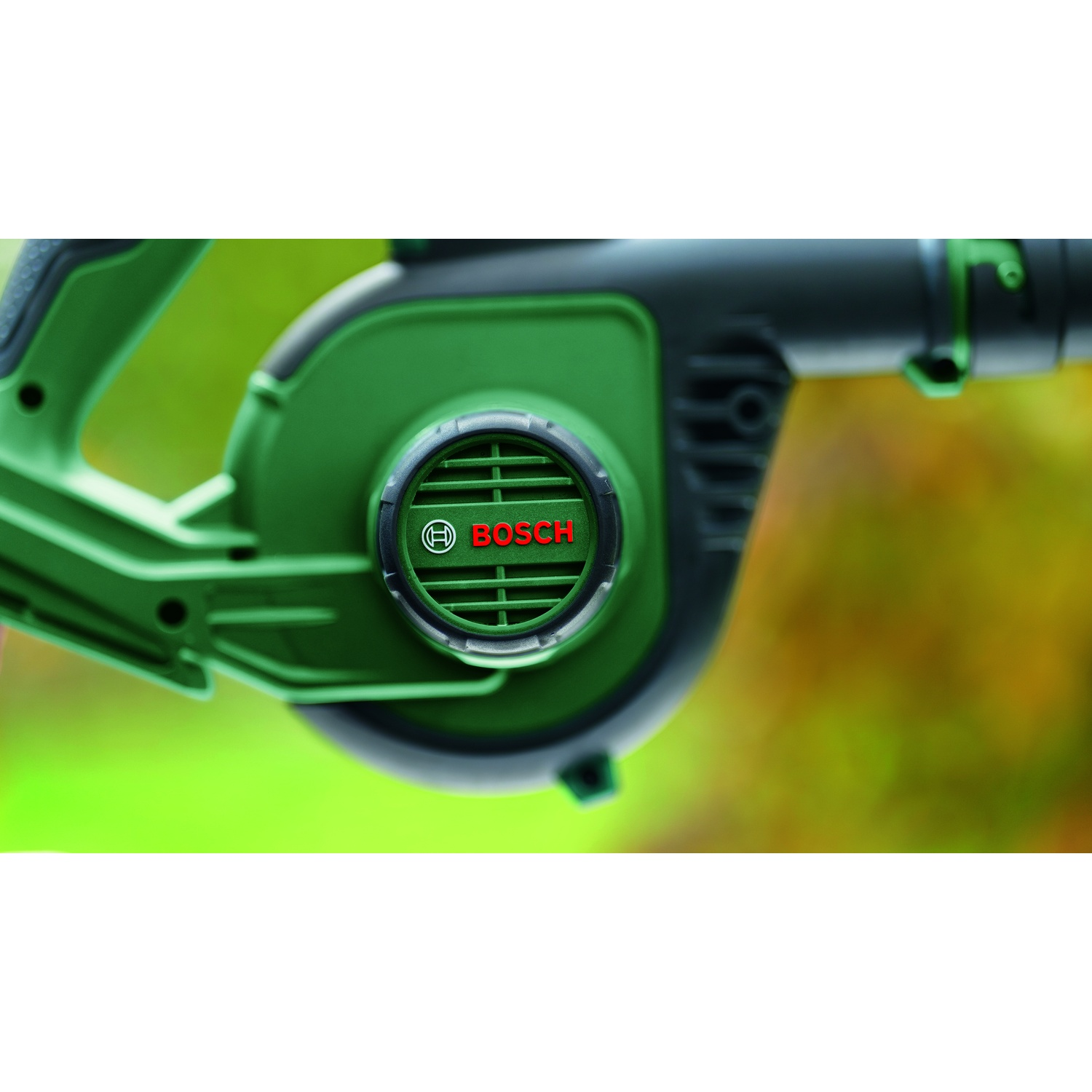 Primo piano di un soffiatore di foglie Bosch verde e nero. Il logo Bosch è rosso. Lo sfondo è verde e giallo sfocato.
