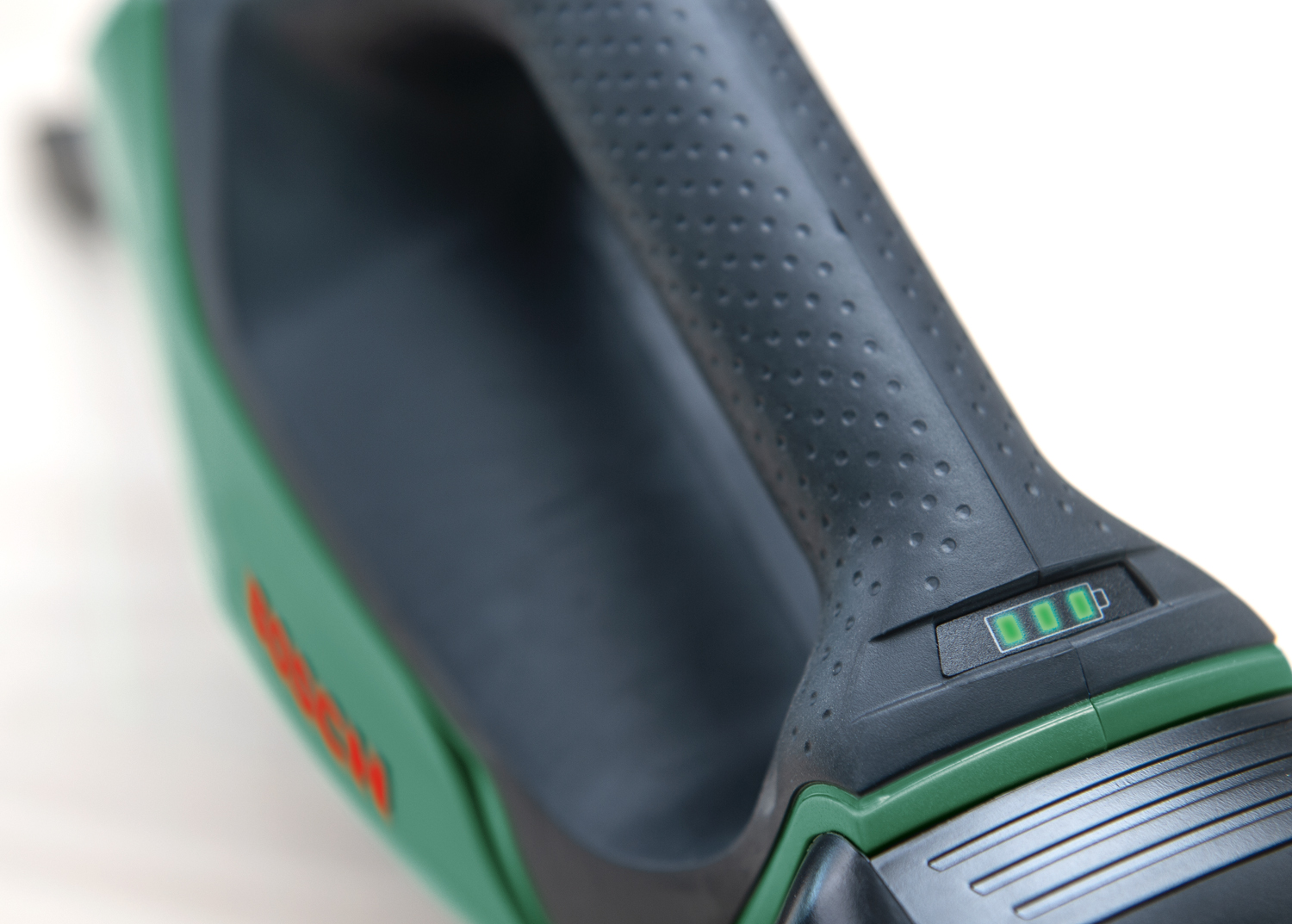 Primo piano di un elettroutensile verde e nero con un indicatore di batteria che mostra tre barre verdi.