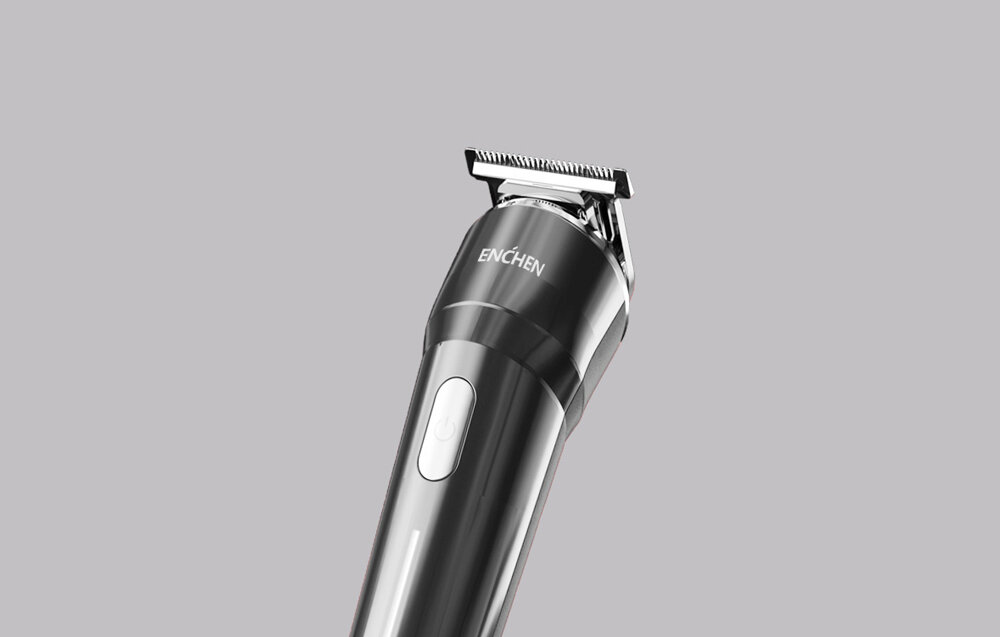 Czarna i srebrna maszynka do włosów Enchen na szarym tle. Trymer jest skierowany w górę.