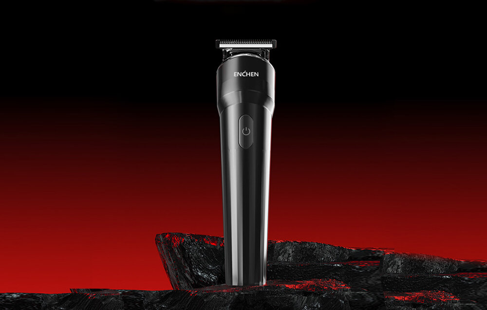 Czarna i srebrna maszynka do golenia Enchen stoi na szorstkiej, czarnej powierzchni na tle czerwono-czarnego gradientu.