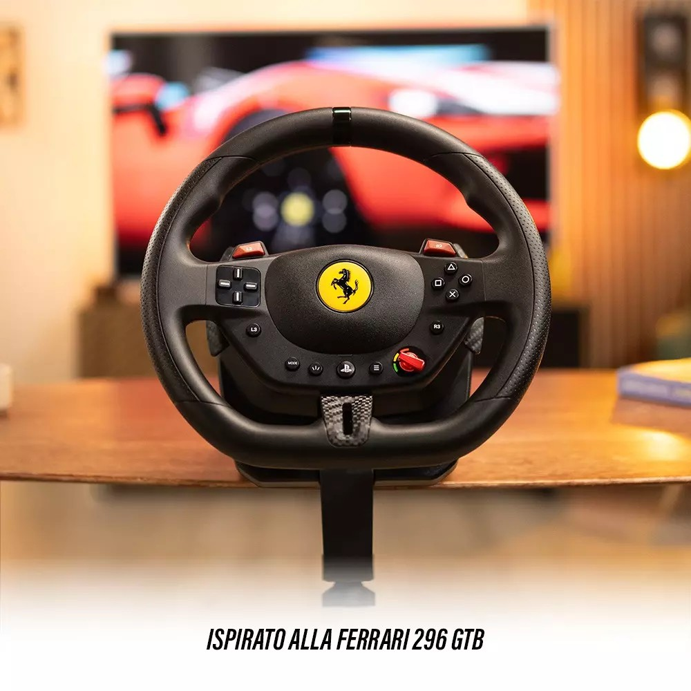 Un volante nero Ferrari, con pulsanti rossi e logo giallo, poggia su una superficie di legno. Sullo sfondo una TV con un'auto rossa.