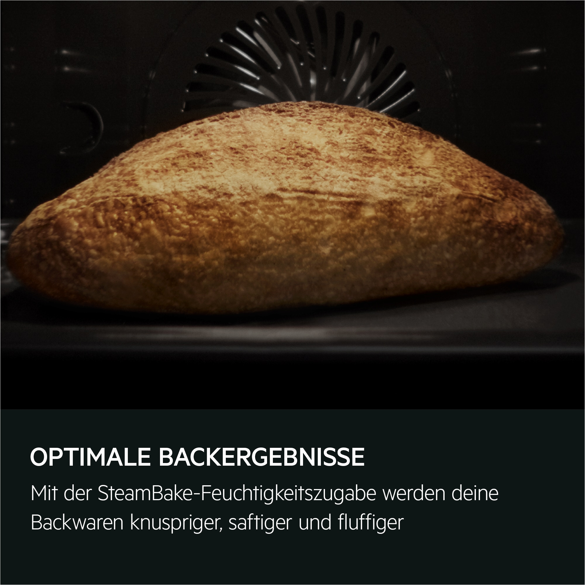 Ein Brotlaib im Ofen. Das Brot ist braun und hat eine Kruste. Der Ofeninnenraum ist dunkel.