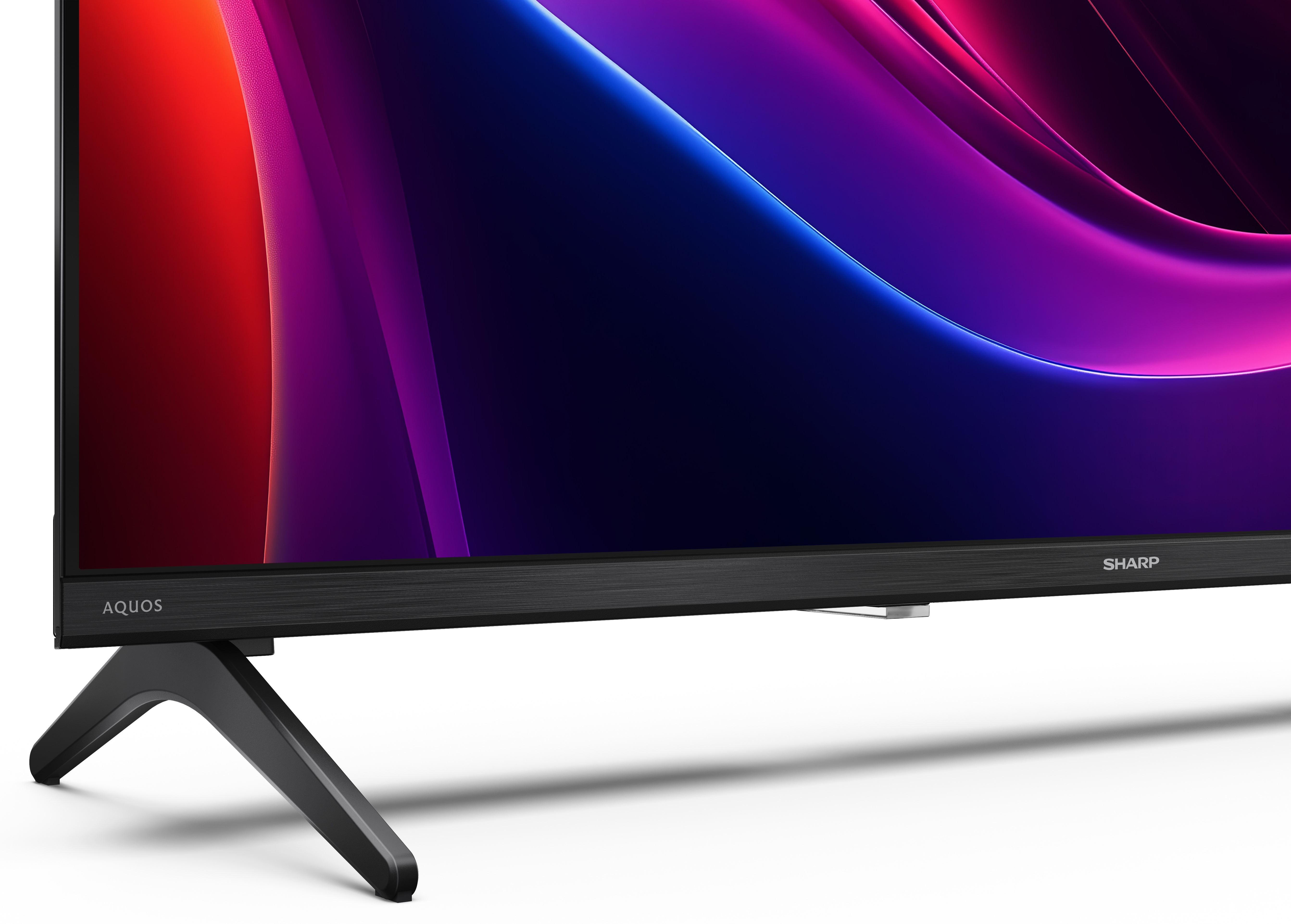 Czarny telewizor Sharp Aquos. Ekran wyświetla kolorowe abstrakcyjne kształty. Telewizor stoi na czarnym, kątowym stojaku.
