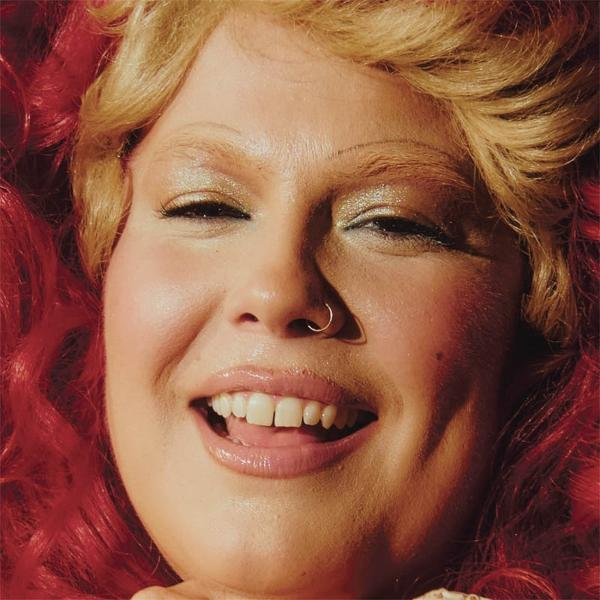 Nahaufnahme einer Frau mit blondem Haar, roten Locken und Glitzer-Lidschatten.