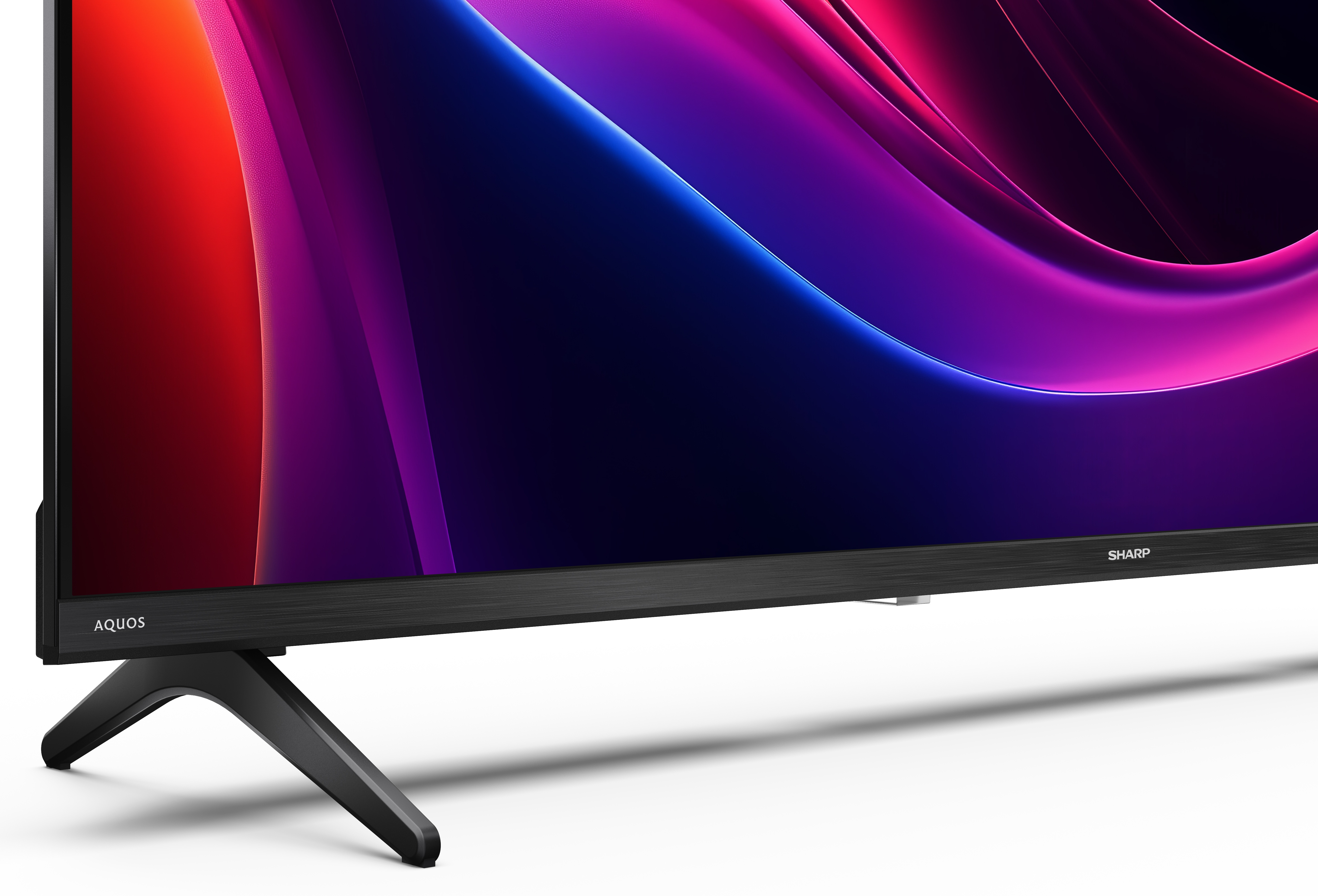 Zbliżenie telewizora z abstrakcyjną, kolorową grafiką. Telewizor ma czarną podstawę i ramę.