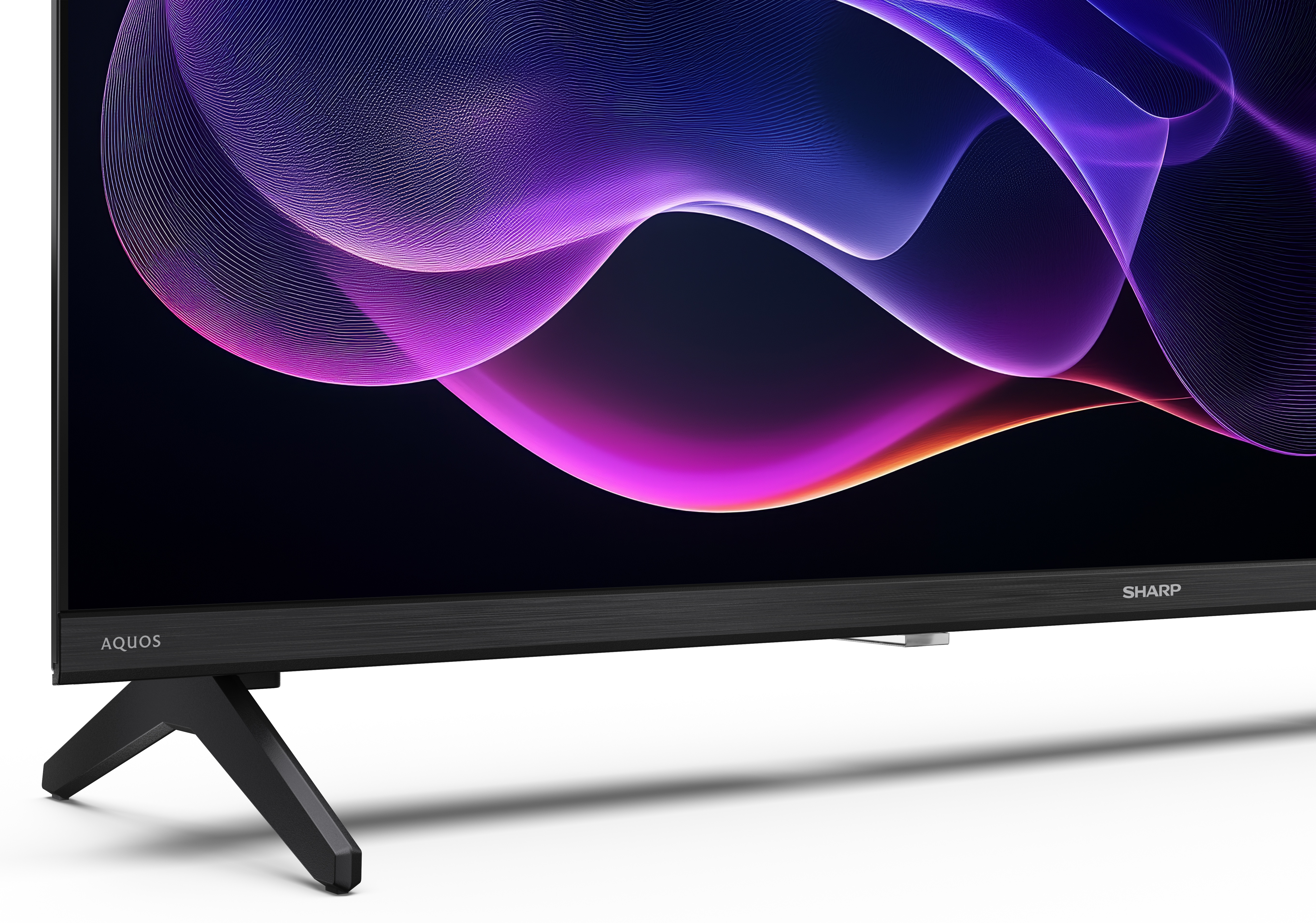 Telewizor Sharp Aquos wyświetla fioletowo-pomarańczowy abstrakcyjny wzór. Ma czarną podstawę i ramę, na białej powierzchni.