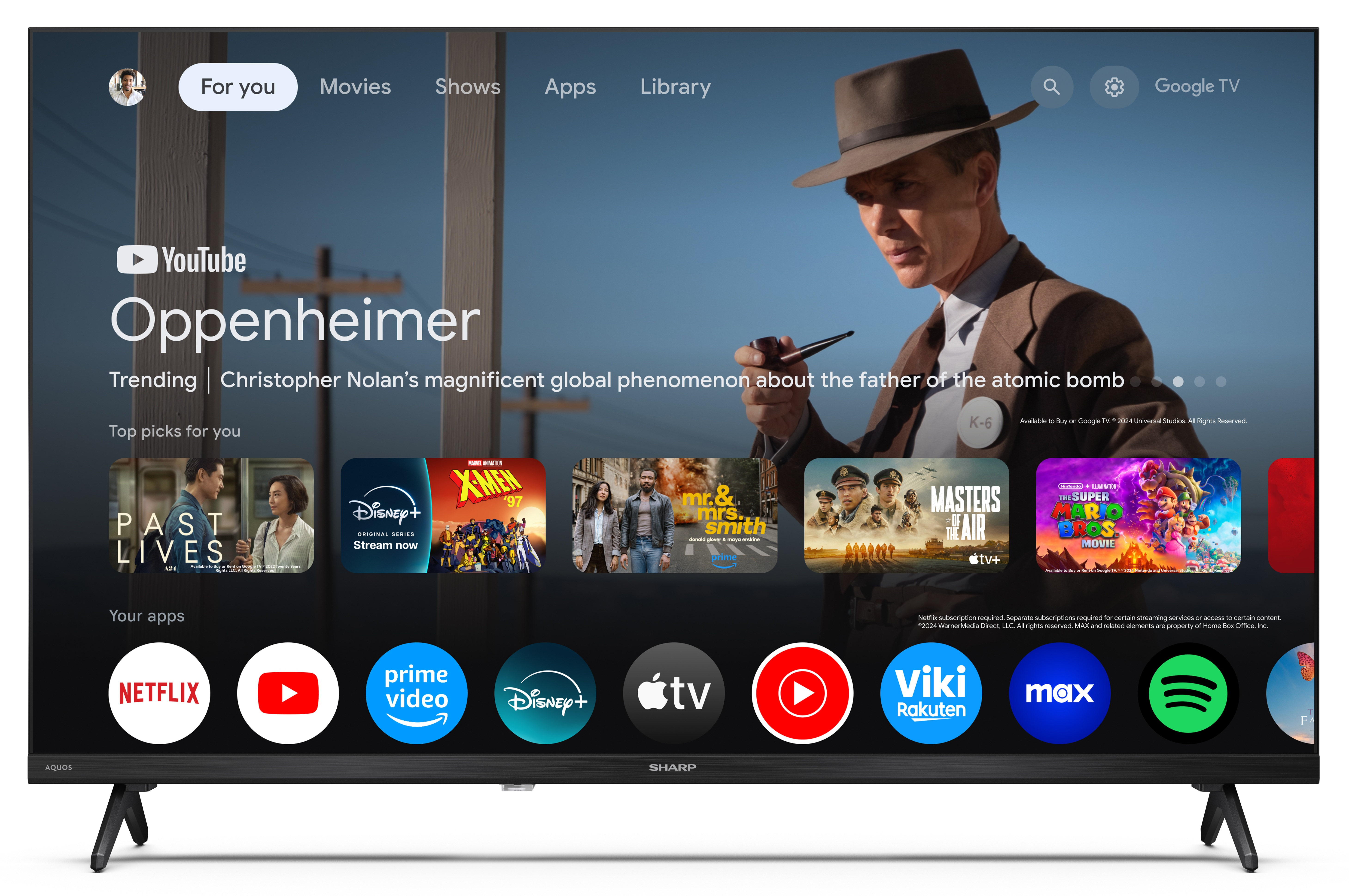 Telewizor Sharp wyświetla aplikację YouTube, film Oppenheimer i inne aplikacje. Widoczny mężczyzna w kapeluszu.