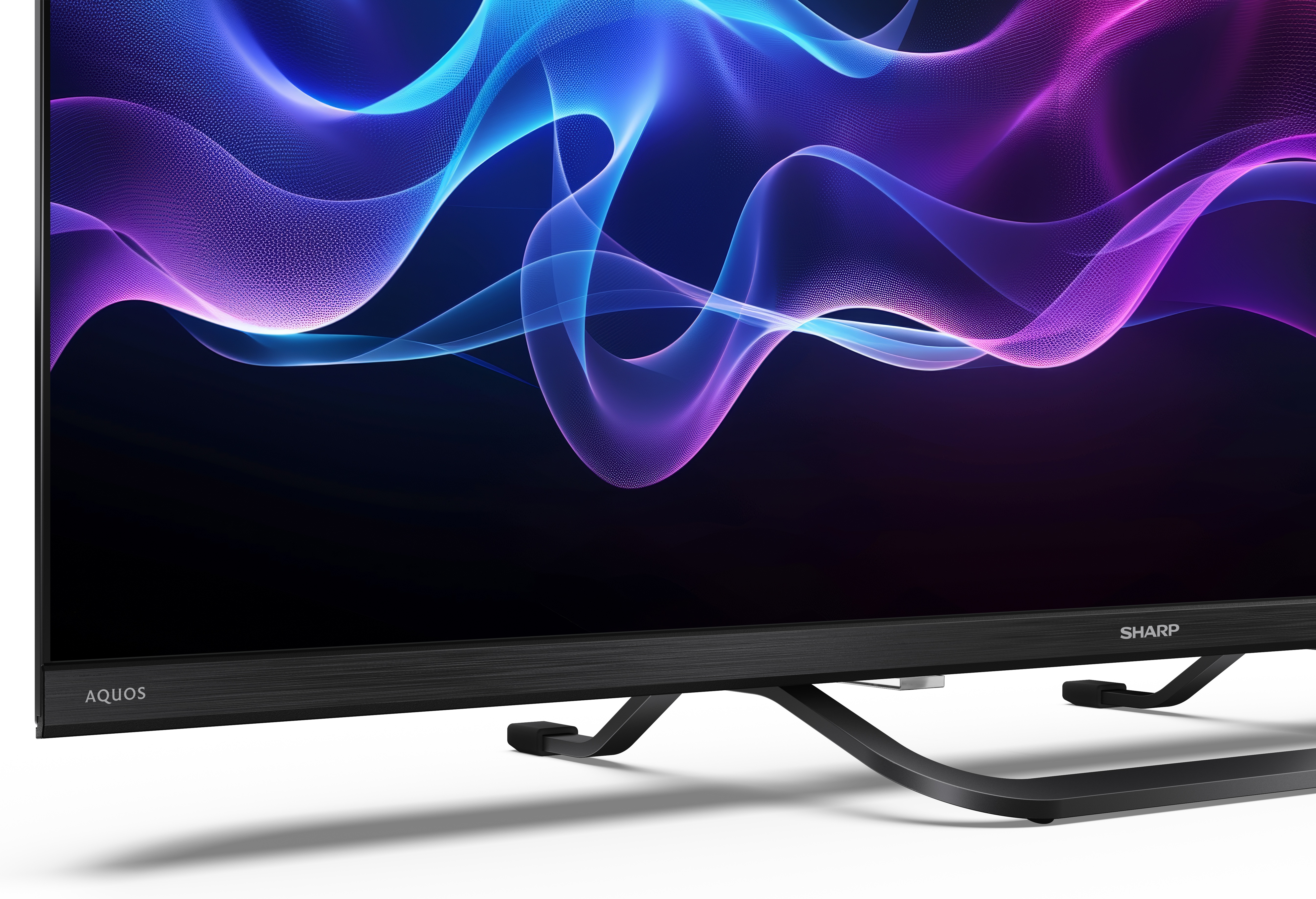 Czarny telewizor Sharp Aquos z abstrakcyjnym niebiesko-fioletowym wzorem fal na ekranie, na białej powierzchni.