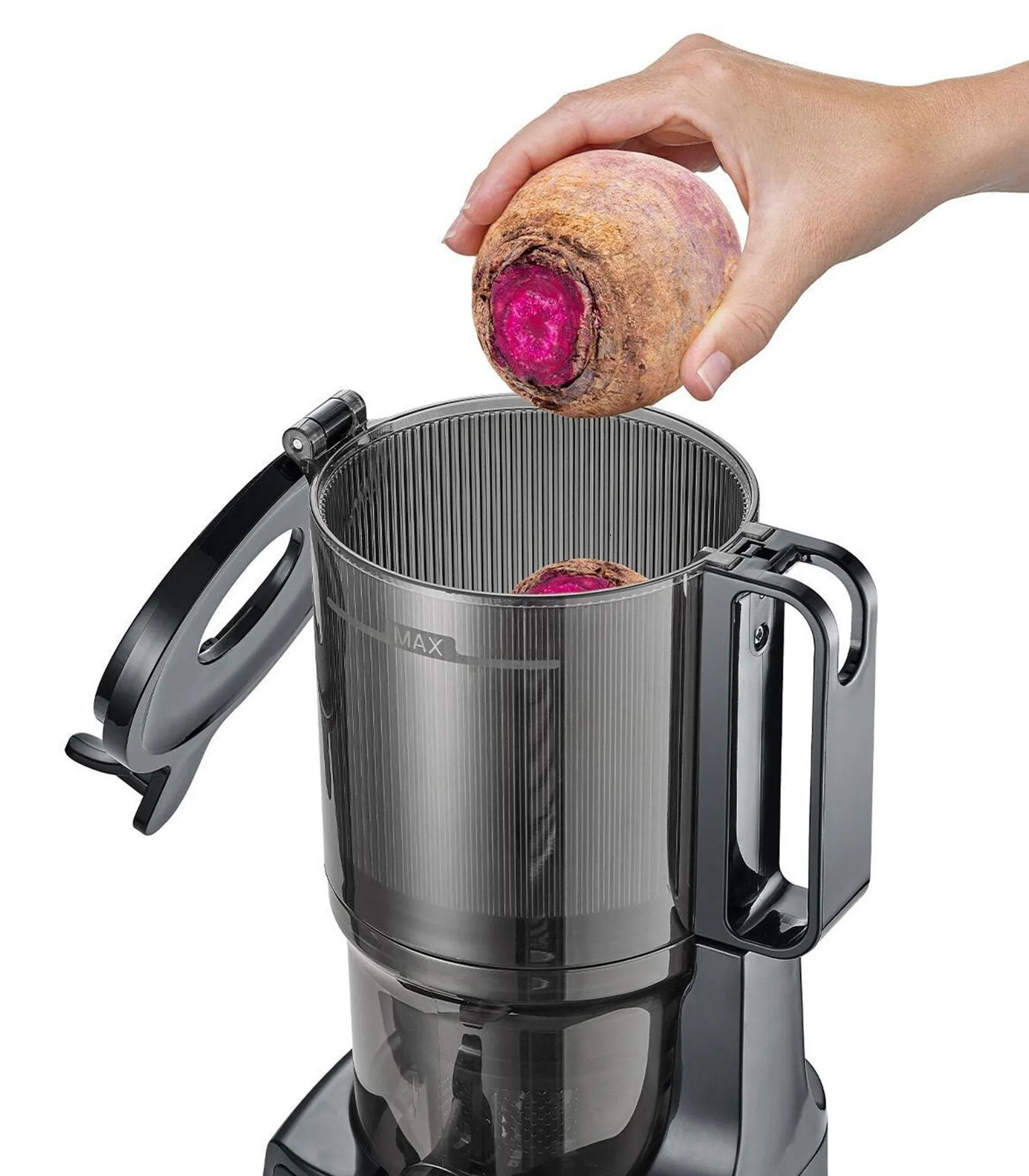 Ręka umieszcza buraka w wyciskarce. Wyciskarka jest czarna, a w środku jest drugi burak.