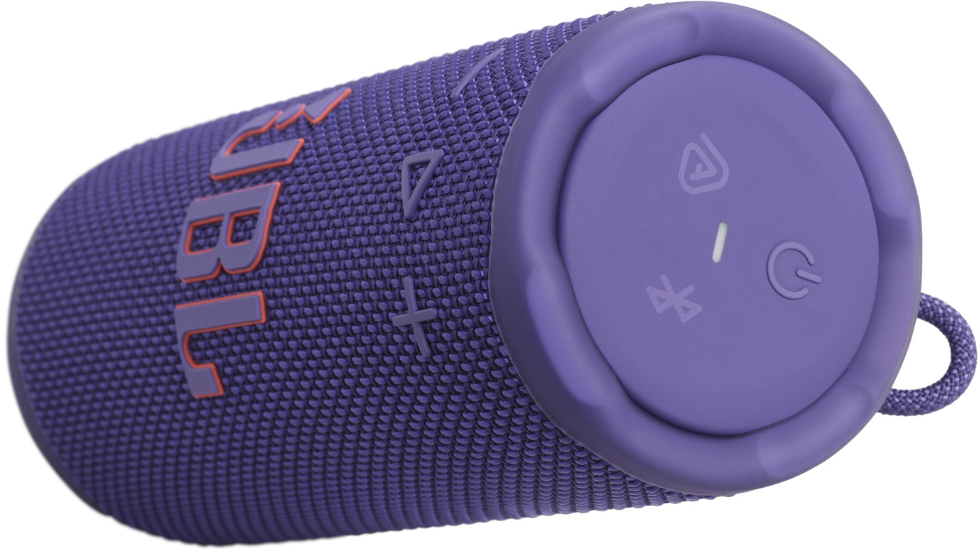 Enceinte JBL violette. L'enceinte porte le logo JBL en orange et des boutons de commande à l'extrémité. Une boucle en tissu est visible.