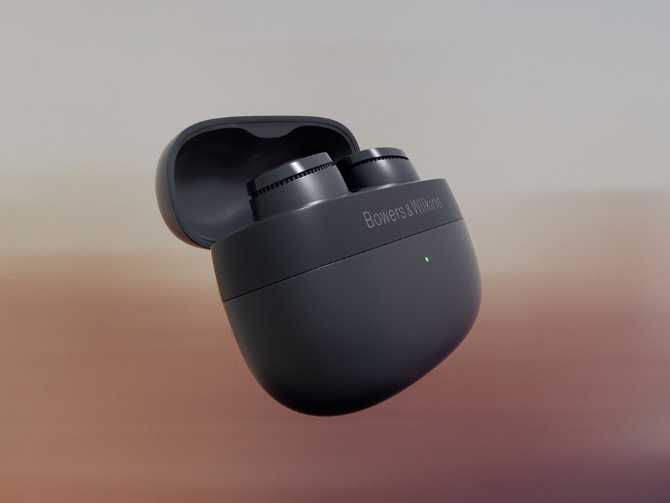 Para ciemnoszarych słuchawek Bowers & Wilkins w otwartym etui ładującym na rozmytym pomarańczowo-beżowym tle.