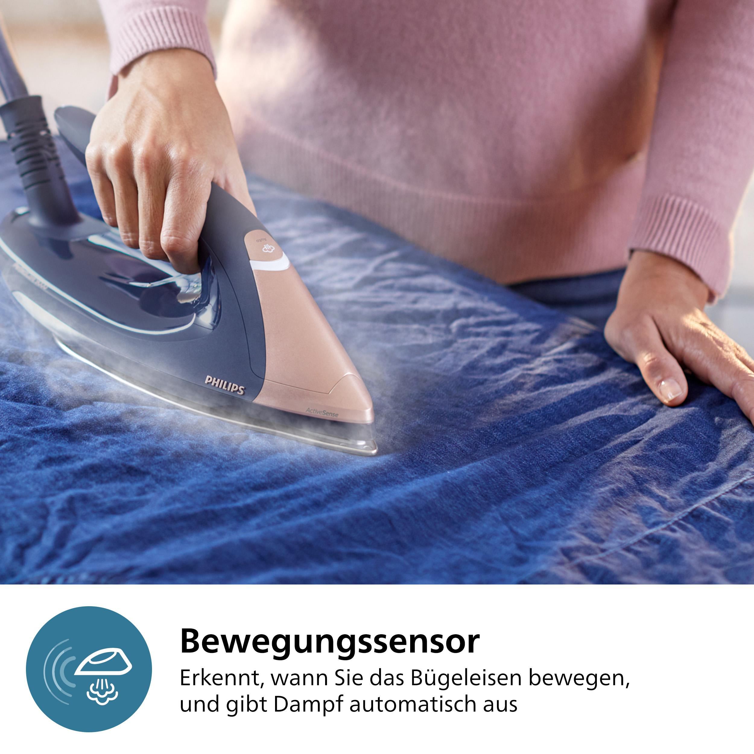 Eine Person bügelt blauen Stoff mit einem Philips-Bügeleisen. Dampf ist sichtbar. Das Bügeleisen ist marineblau und roségold.