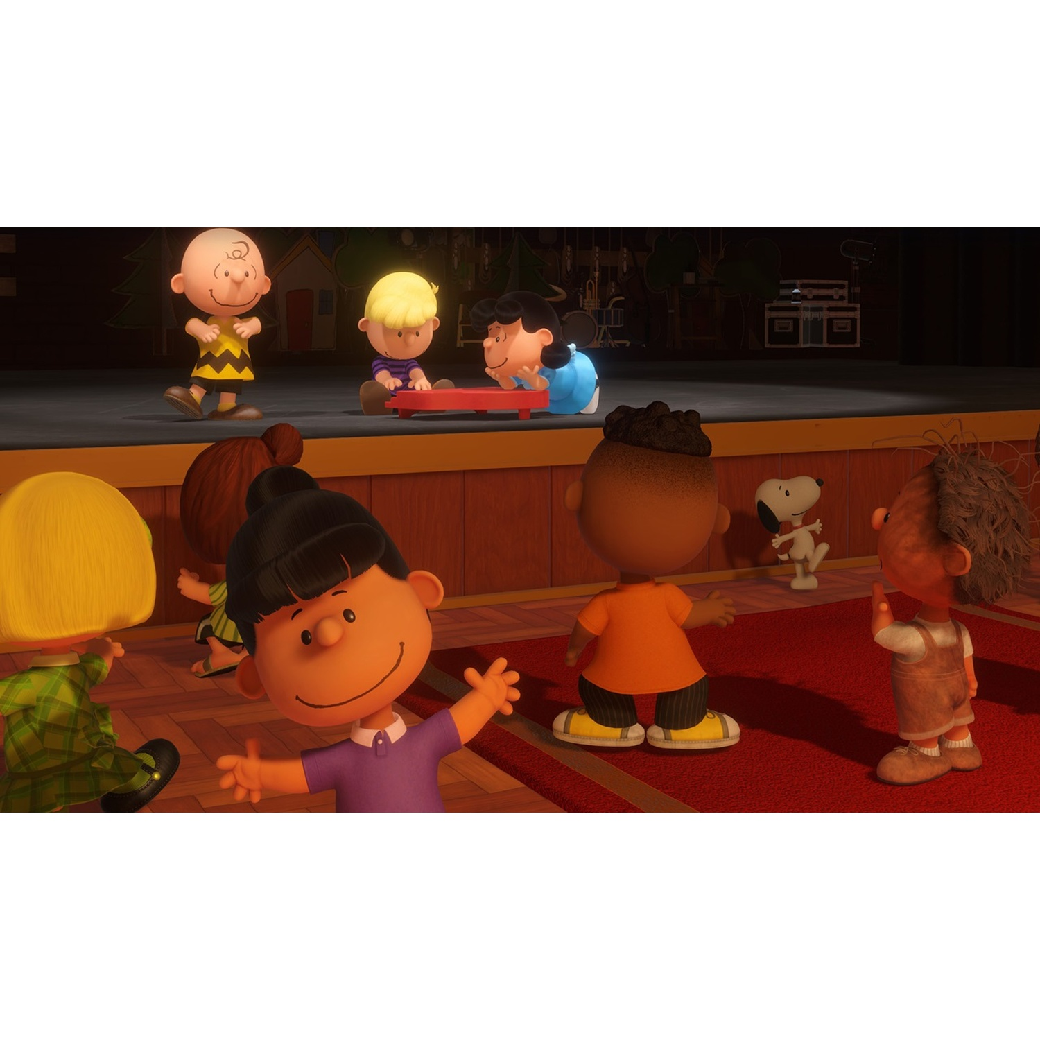 Kinderen, waaronder Charlie Brown en Snoopy, staan op het podium en in het publiek. Rode loper, houten podium en donkere achtergrond.