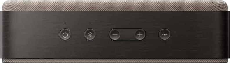 Nahaufnahme eines dunkel gefärbten Lautsprechers. Zu den Tasten gehören Ein/Aus, Bluetooth, Lautstärke erhöhen/verringern und eine Multi-Dot-Taste. Die Oberseite ist aus beigem Stoff.