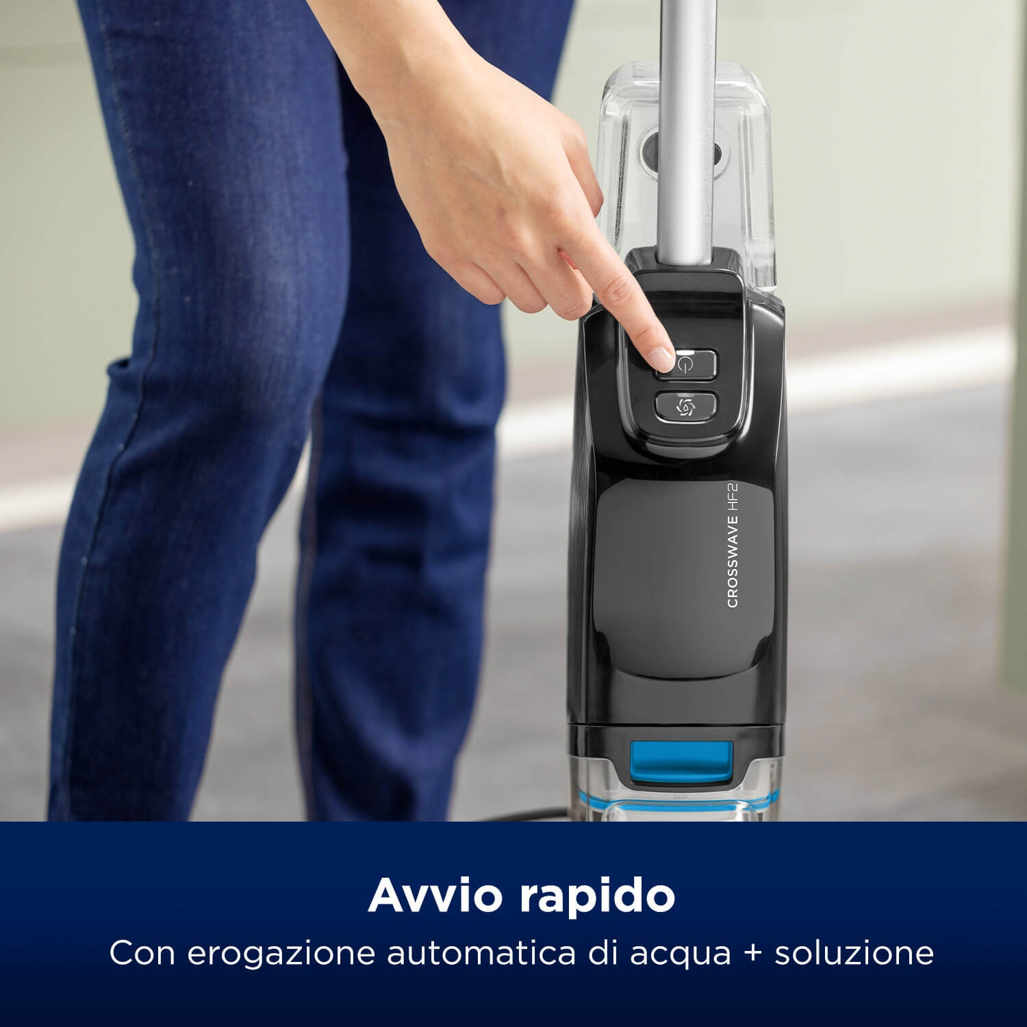 Una persona preme un pulsante su un pulitore per pavimenti nero e argento. Il pulitore è etichettato 'CROSSWAVE HF2'.