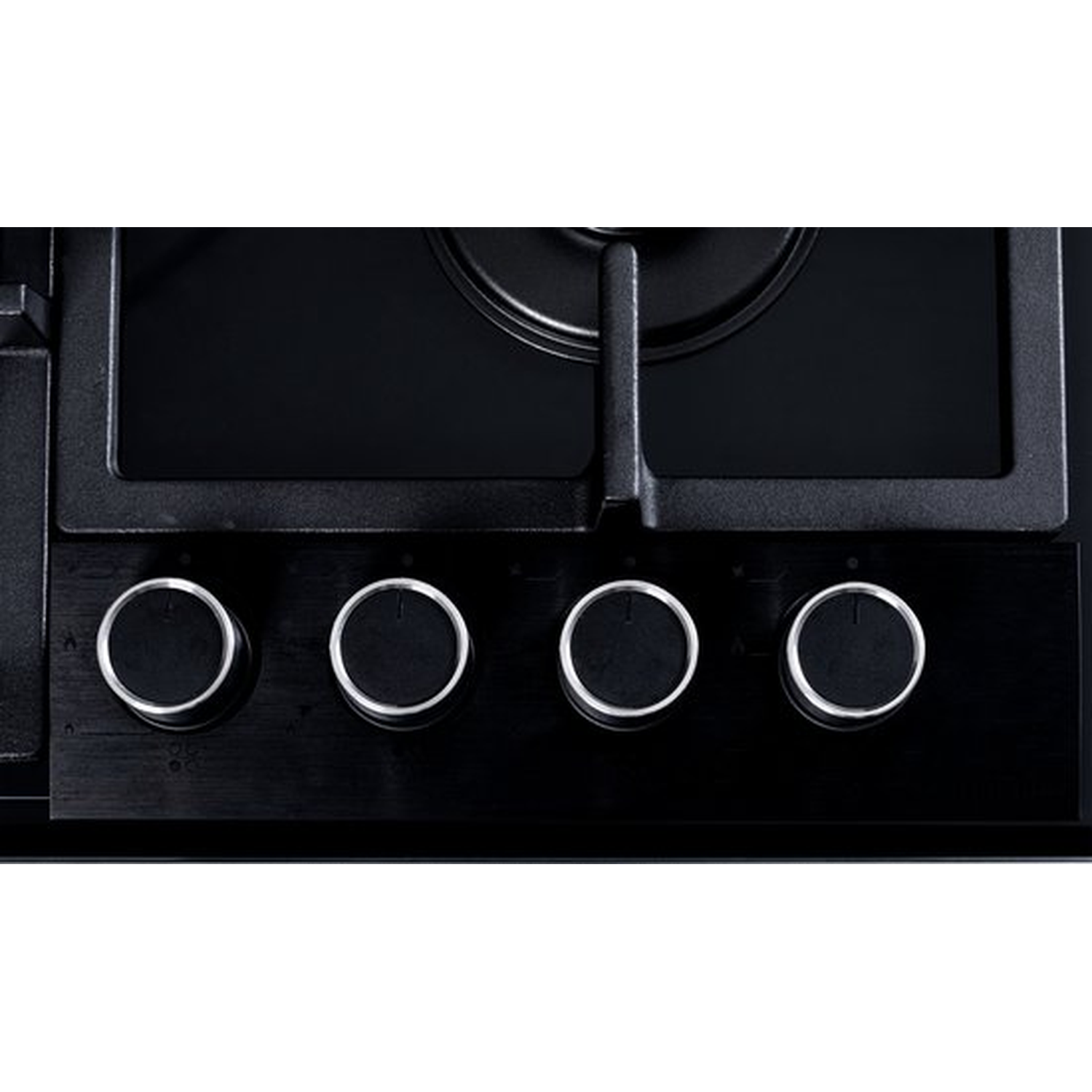 Close-up of a black stovetop with four control knobs and burners. Silver rings outline the knobs. The background is black.