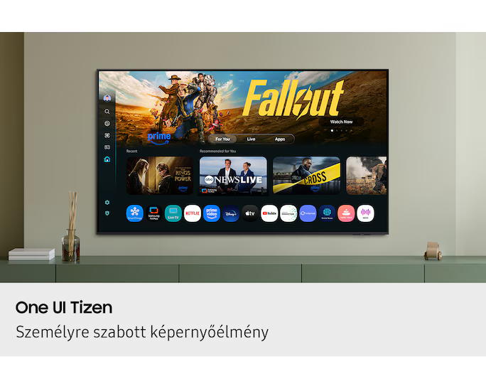 A TV a 'Fallout' sorozatot jeleníti meg. A képernyő alkalmazásokat és műsorokat mutat. Zöld szekrényen van dekorációval.