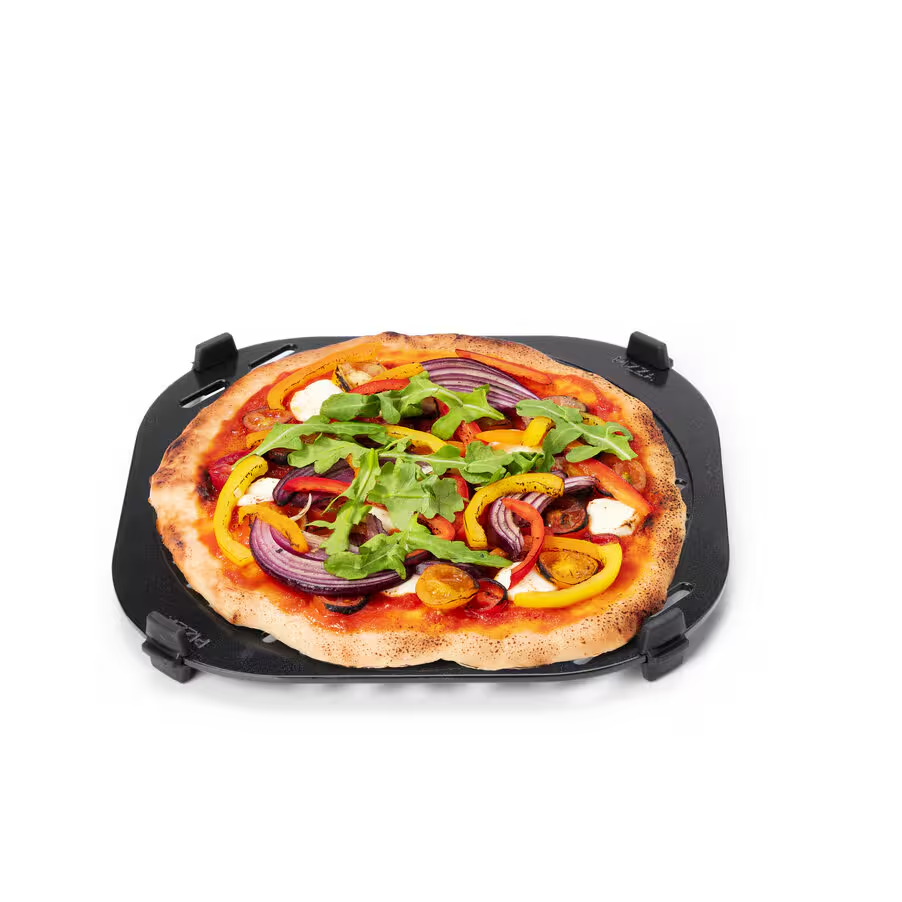 Pizza egy fekete tálcán zöldségekkel és rukkolával. A pizzán piros, sárga és lila zöldségek vannak. Fehér háttér.