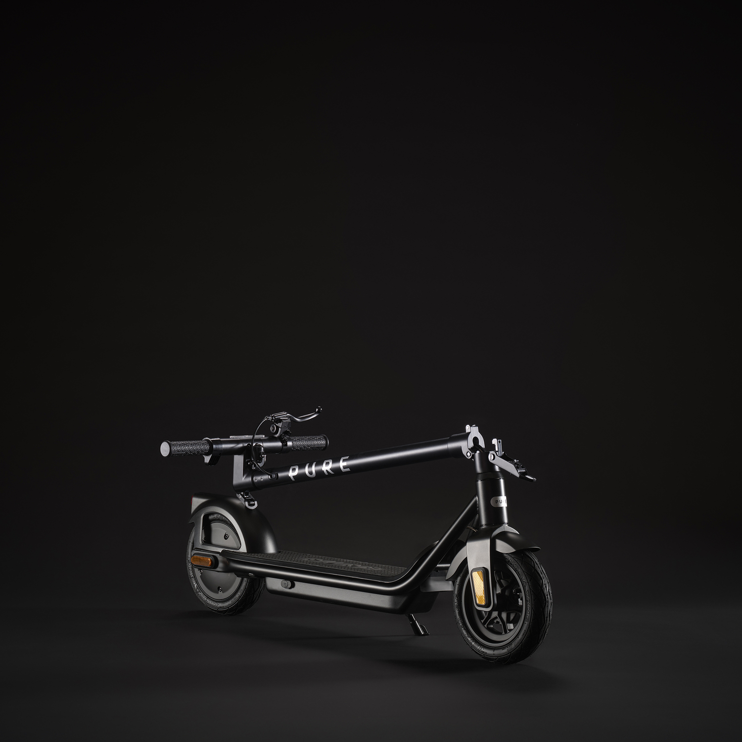 Een zwarte Pure elektrische scooter staat op een zwart oppervlak tegen een zwarte achtergrond. De scooter staat iets naar links.