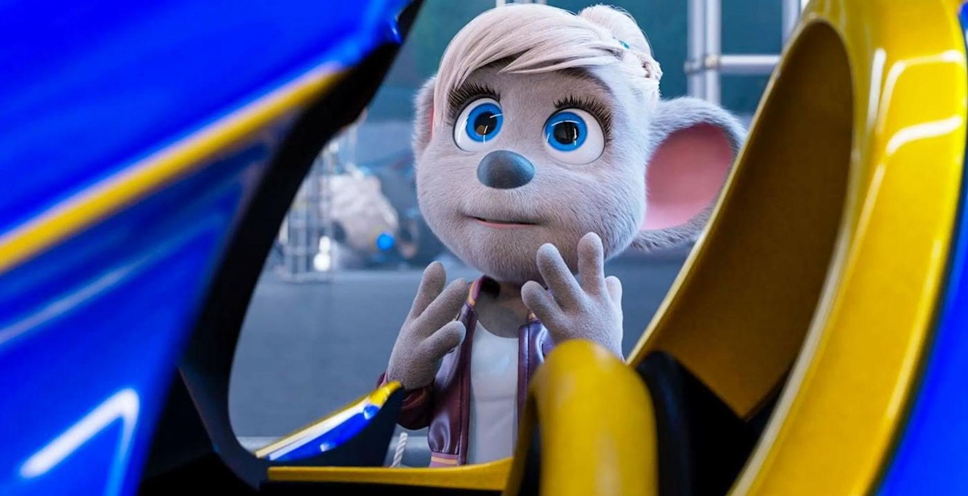 Animierte Maus mit hellem Fell, blauen Augen und einer weinroten Jacke, die ein Friedenszeichen macht, in einem gelb-blauen Fahrzeug.