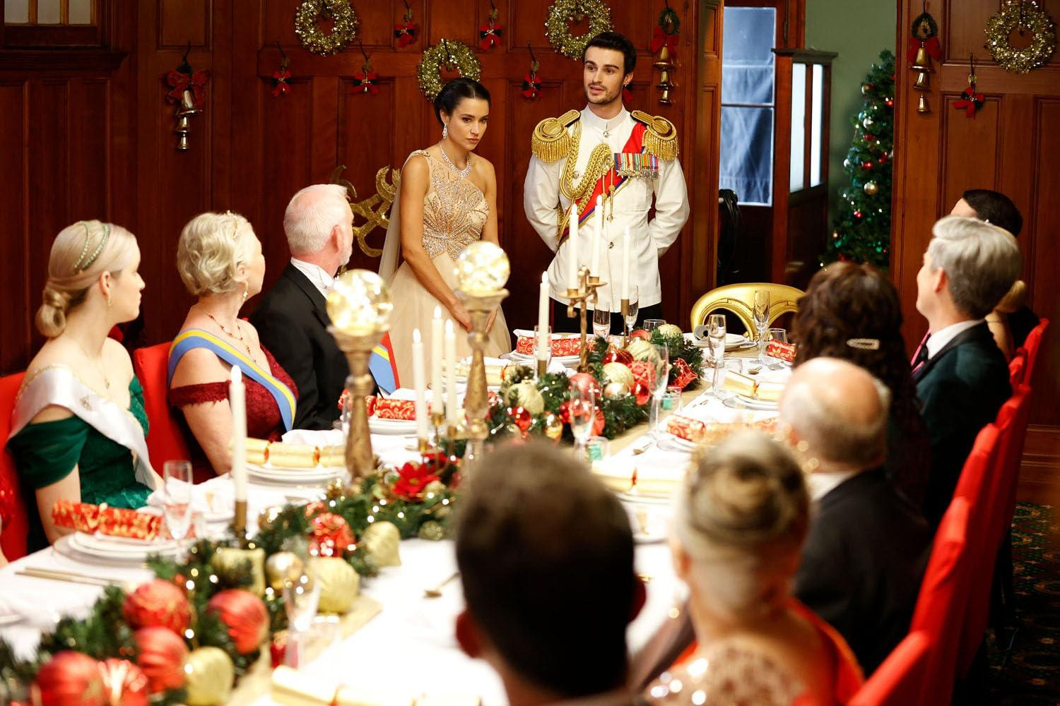 Formelles Abendessen. Mann in Militäruniform steht mit einer Frau in einem goldenen Kleid. Gäste sitzen an einem geschmückten Tisch.