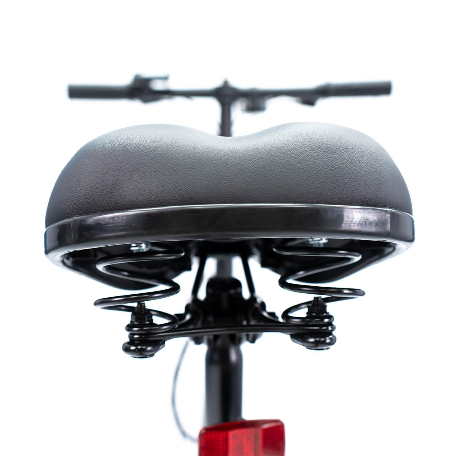 Primer plano de un asiento de bicicleta. Asiento negro con resortes, manillar al fondo y un reflector rojo en la parte inferior.