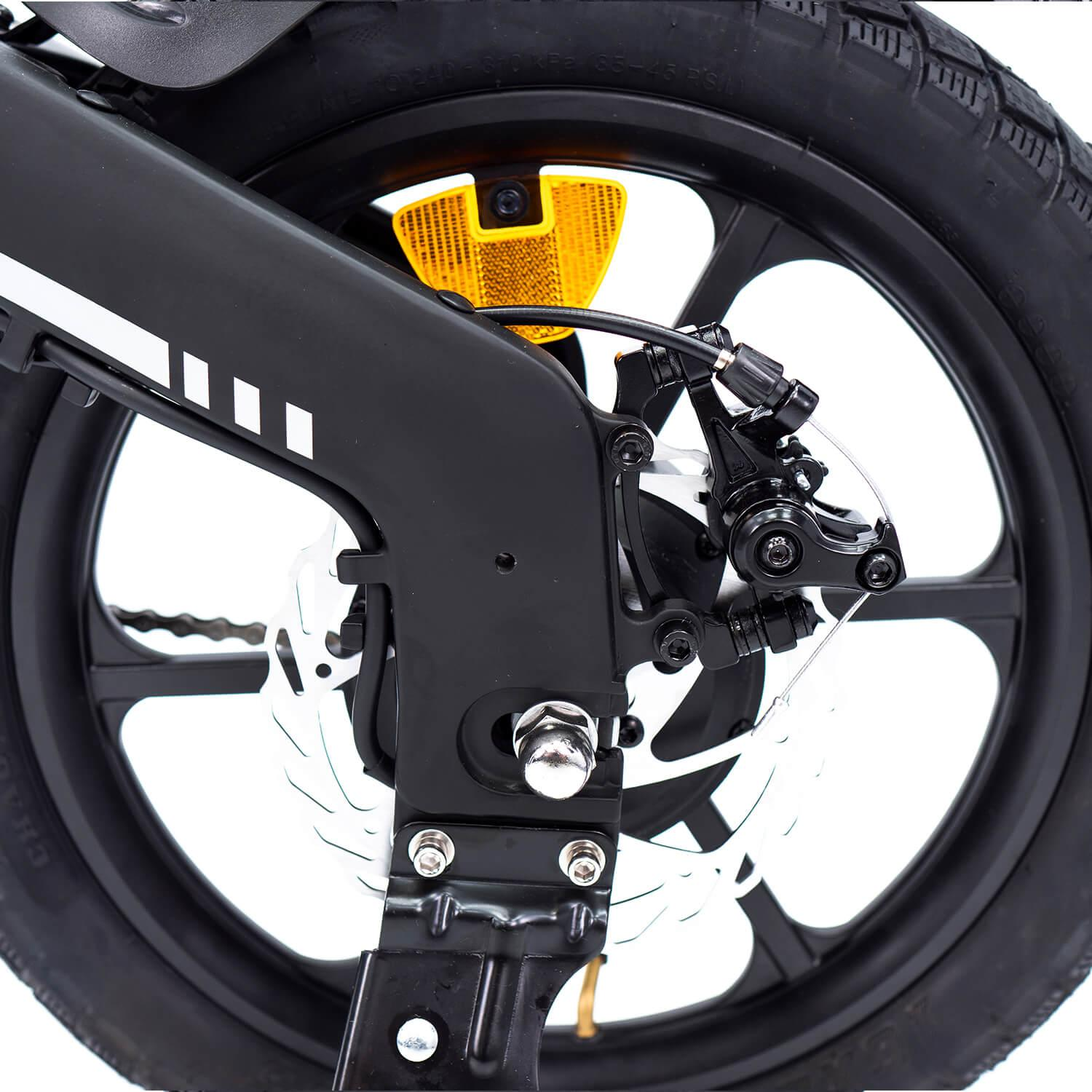 Primer plano de una rueda de bicicleta negra con frenos de disco y un reflector amarillo. El neumático es negro, la llanta es negra con detalles blancos.