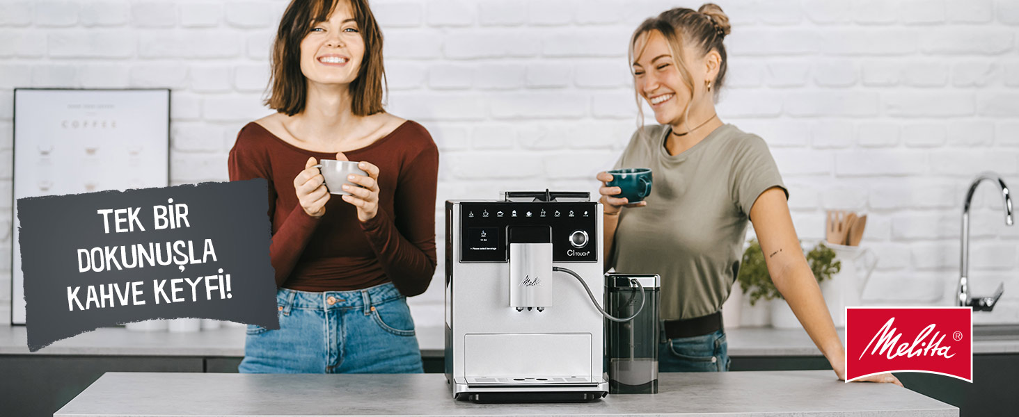 İki kadın, kahve makinesinin yanında fincan tutarak gülümsüyor. Bir Melitta logosu görünür.