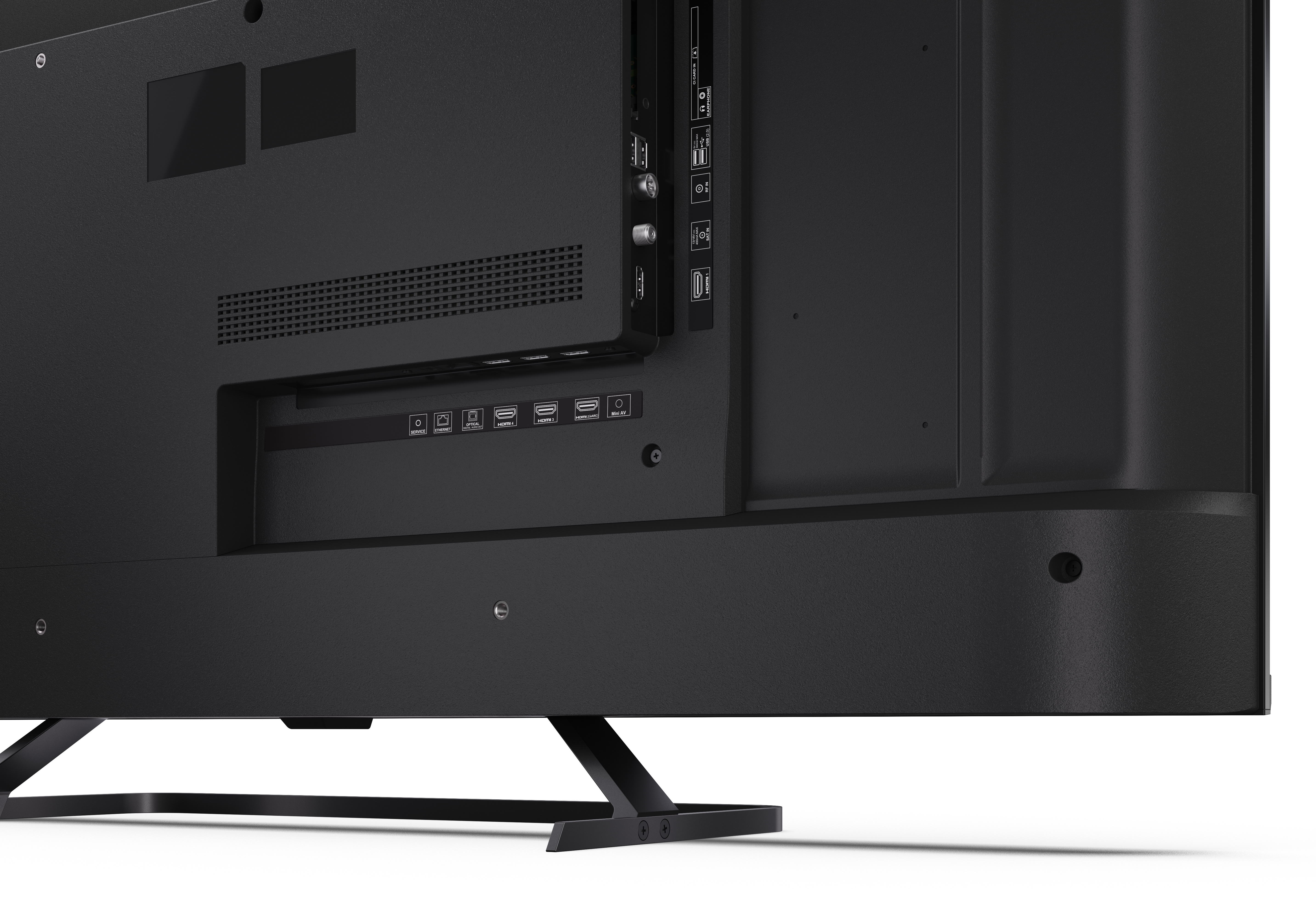 Zbliżenie na tylny panel czarnego telewizora. Widoczne porty, otwory wentylacyjne i podstawka.
