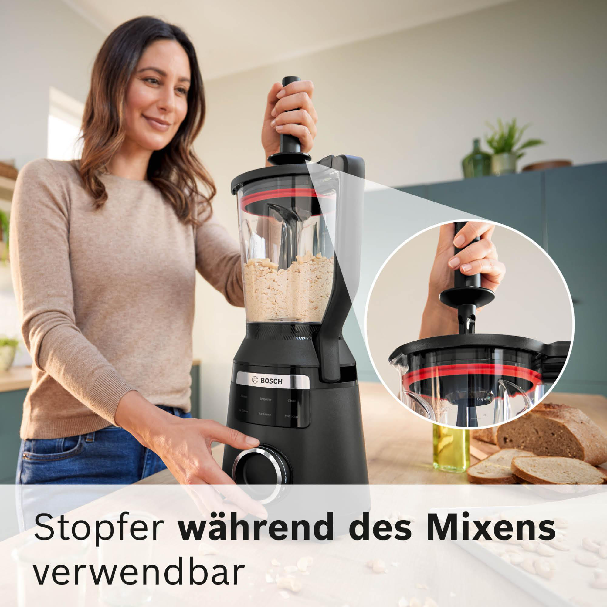 Eine Frau benutzt einen Bosch-Foodprozessor. Der Mixer ist schwarz, hat rote Akzente und enthält Lebensmittel. Brot und Öl sind im Hintergrund.