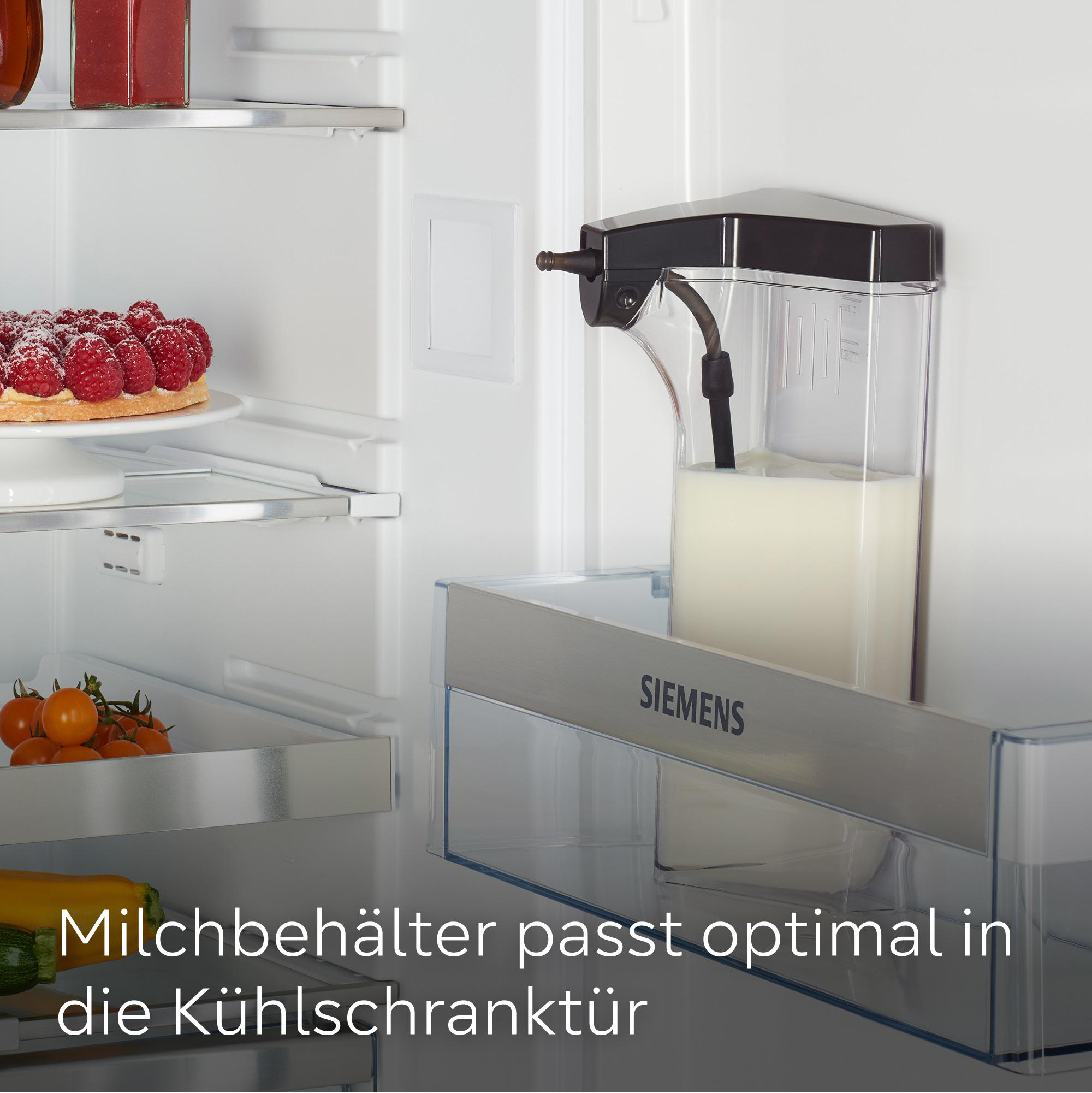 Kühlschrankinnenraum mit Milchspender. Himbeeren auf einem Teller, Kirschtomaten und Zucchini sind ebenfalls sichtbar.