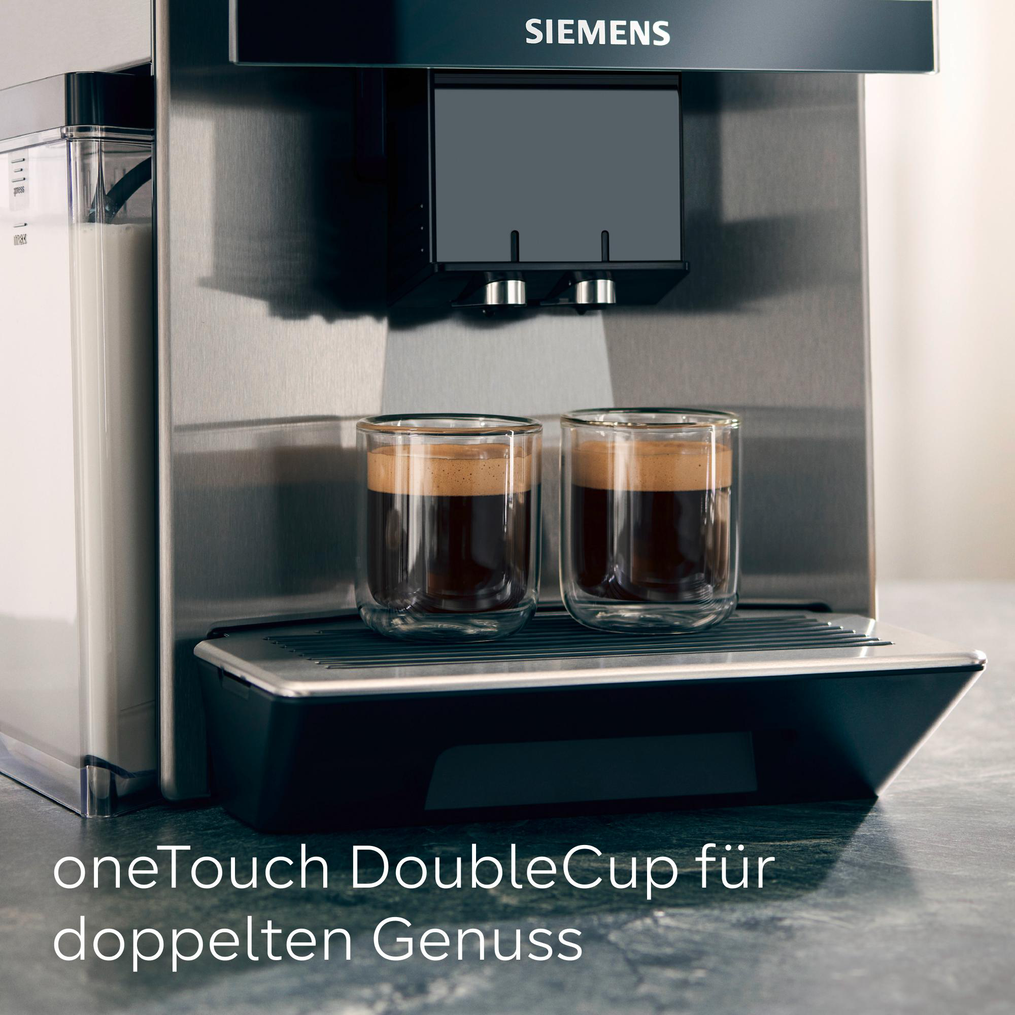 Eine silberne Espressomaschine mit zwei doppelwandigen Gläsern, die mit Kaffee gefüllt sind. Links ist ein Milchbehälter.