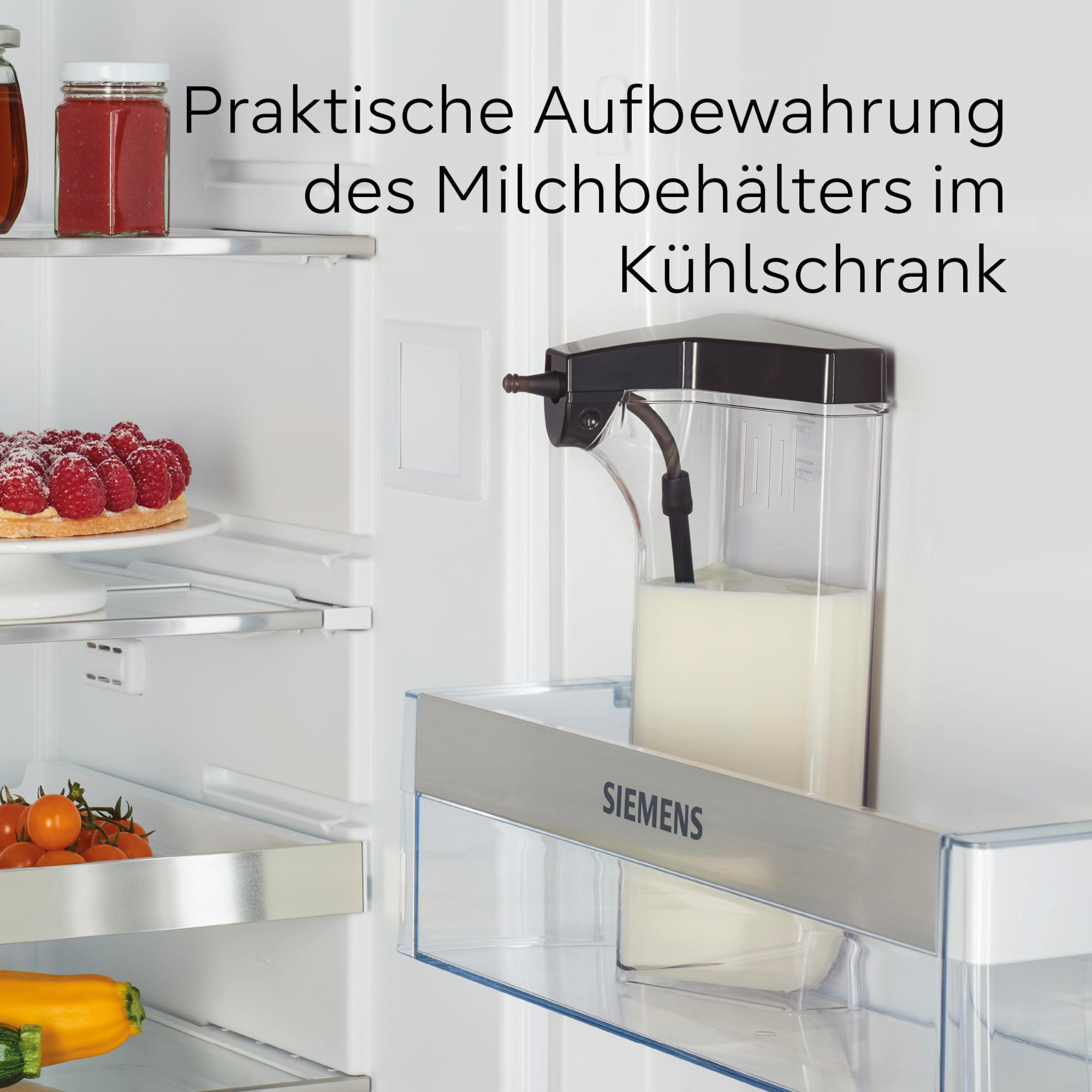 Kühlschrank mit Milchspender, Kuchen, Gläsern und Gemüse. Der Text lautet: Praktische Aufbewahrung des Milchbehälters im Kühlschrank.